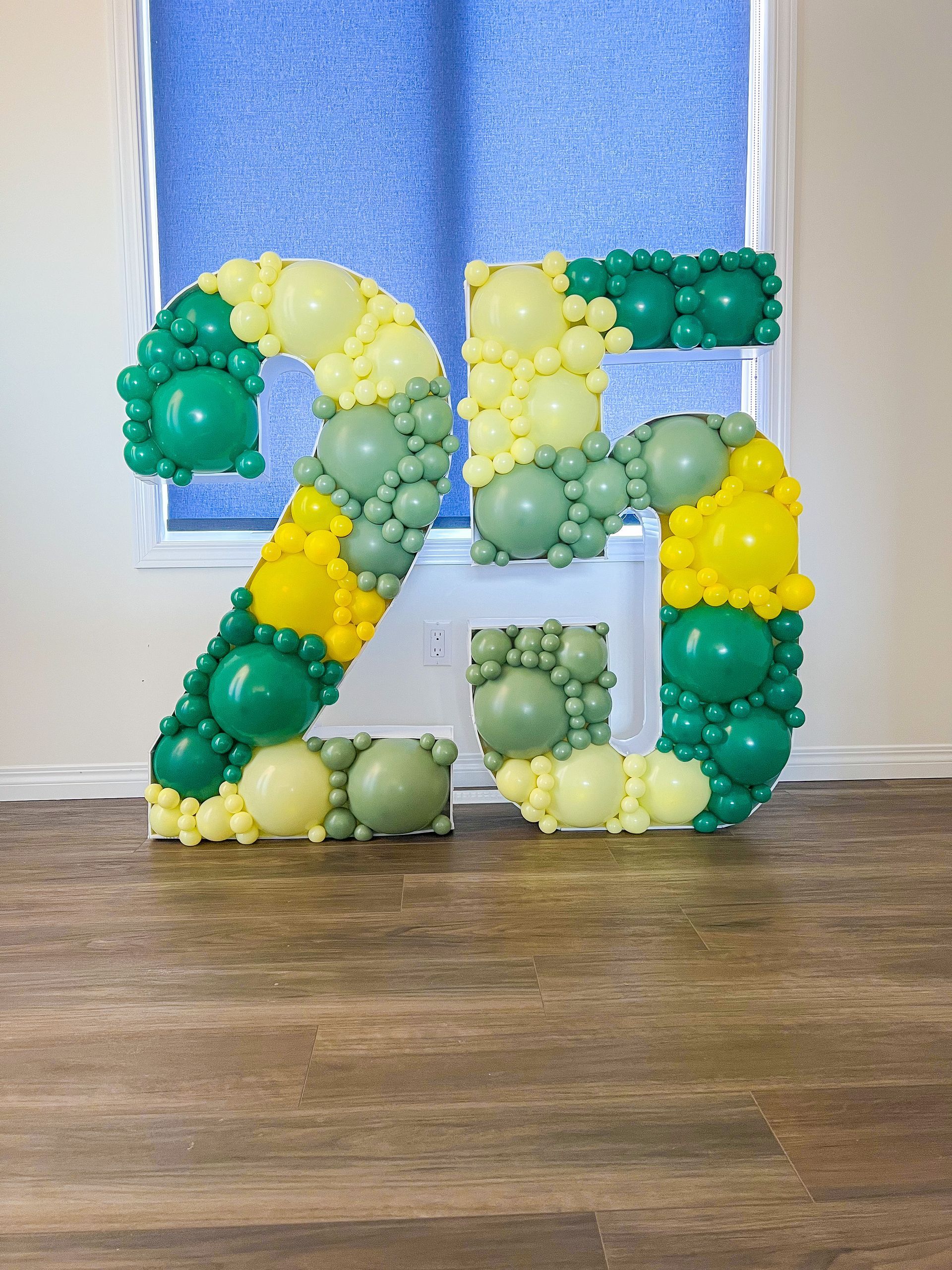 The number 25 is made of green and yellow balloons.