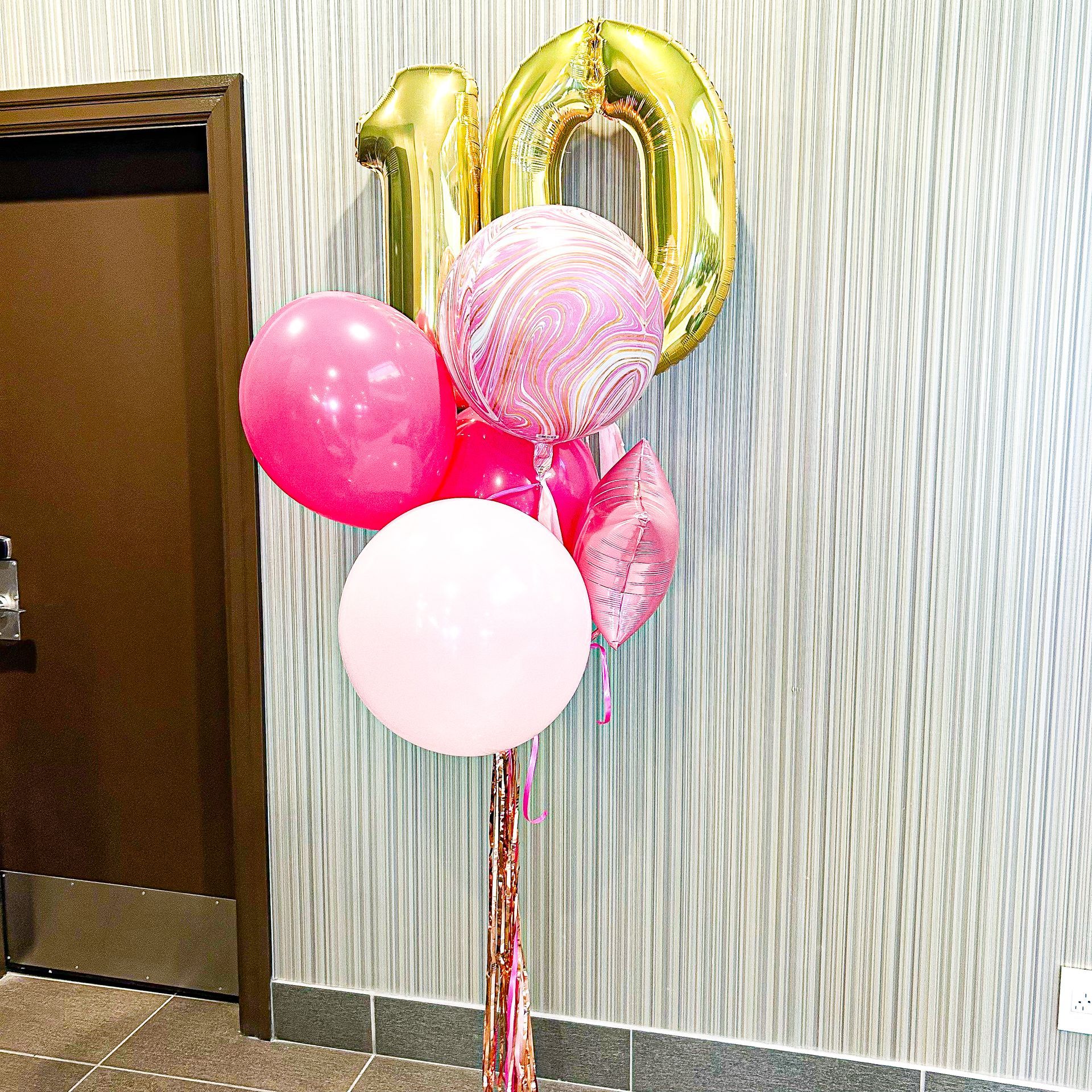 A bunch of pink balloons and a gold number 10