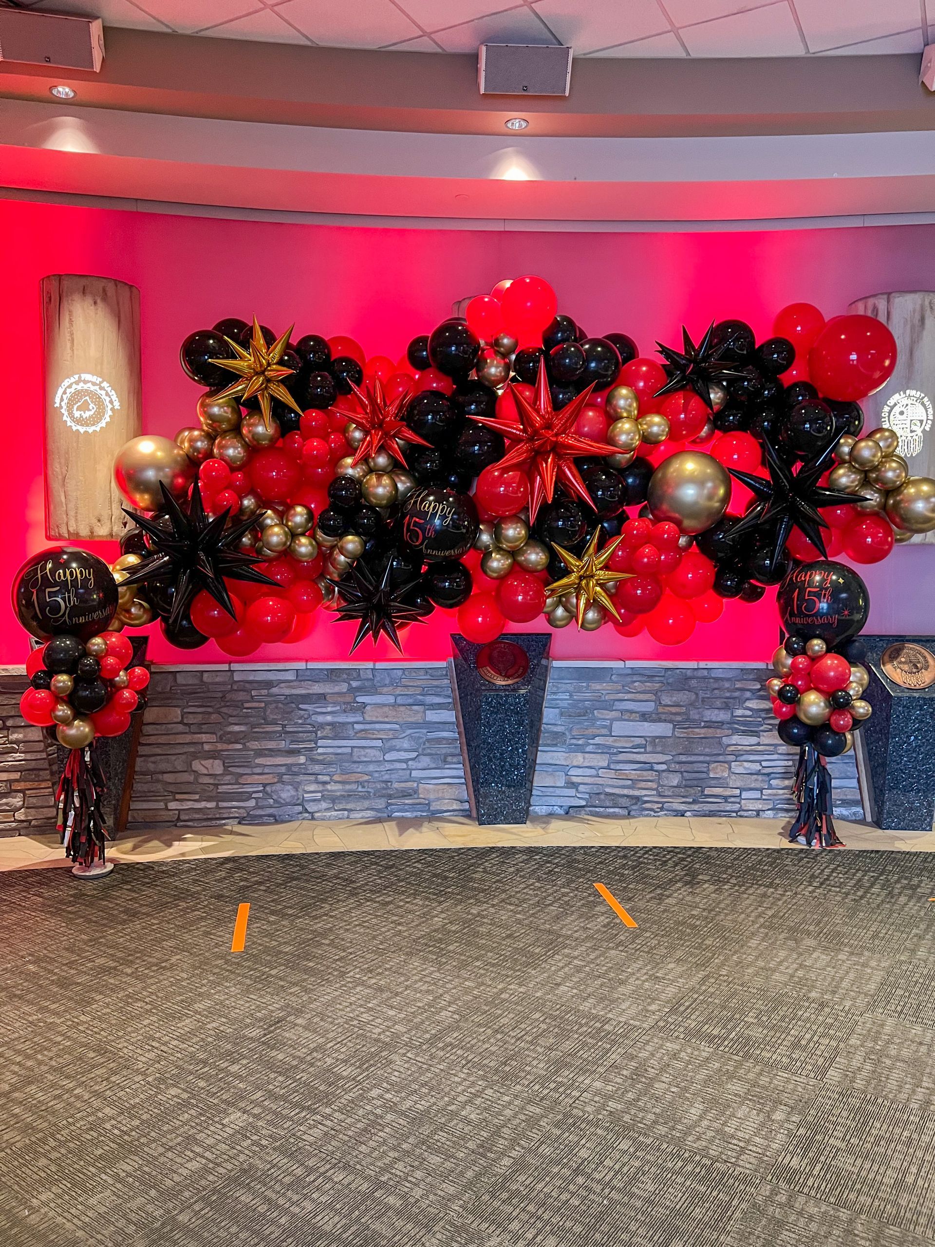 A room filled with red , black and gold balloons.