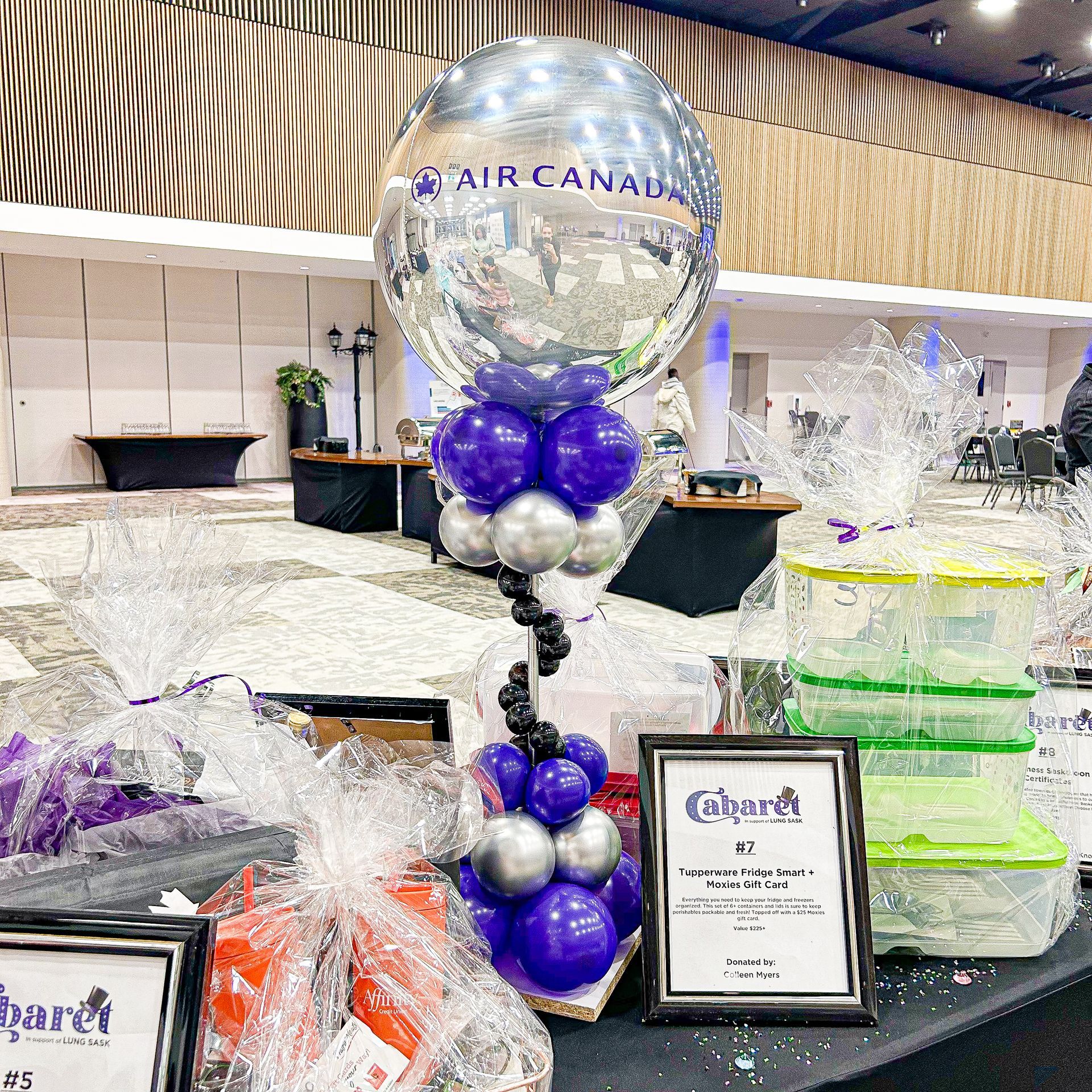A balloon with the word air canada on it is sitting on top of a table with purple and silver balloons.