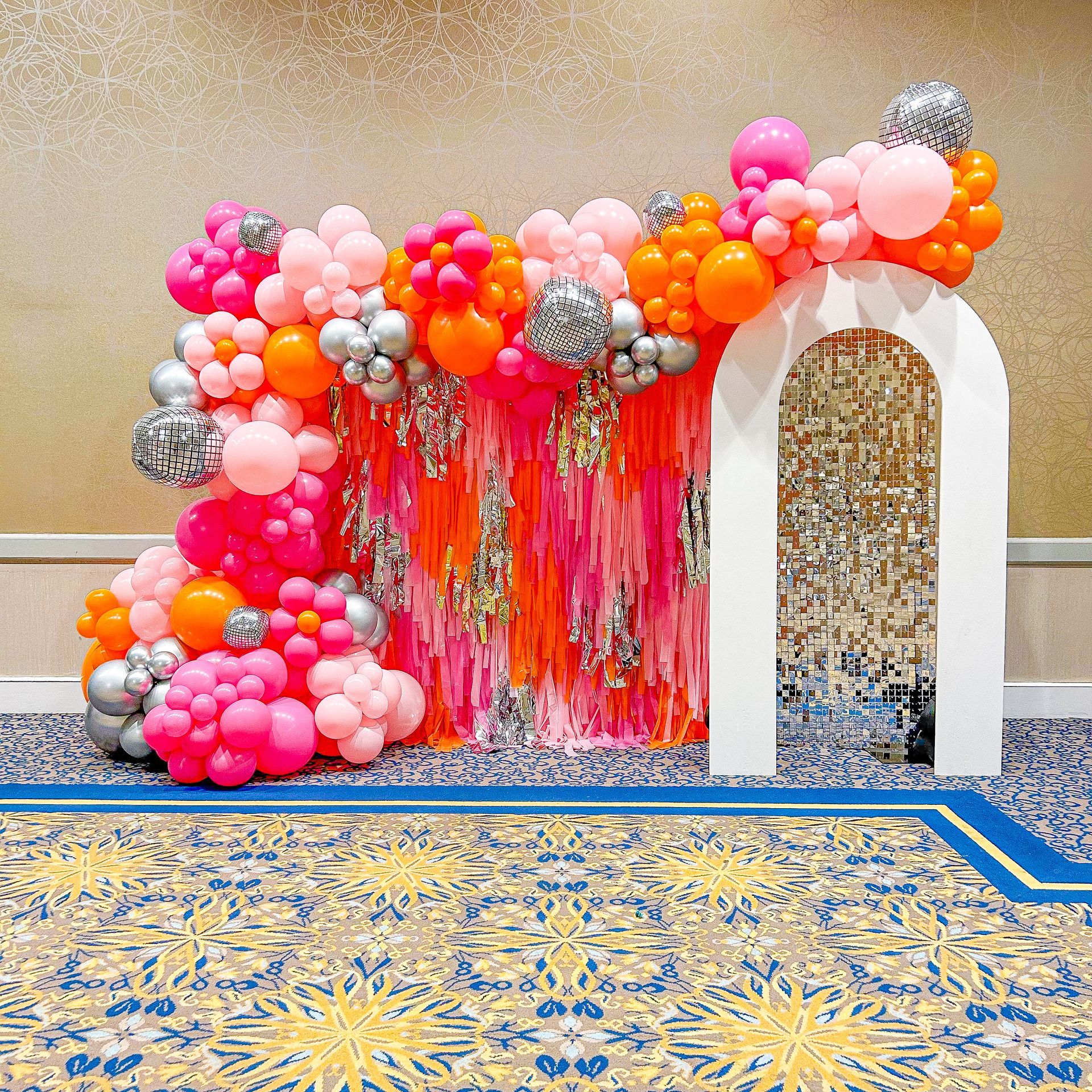 A room filled with balloons and a white arch.