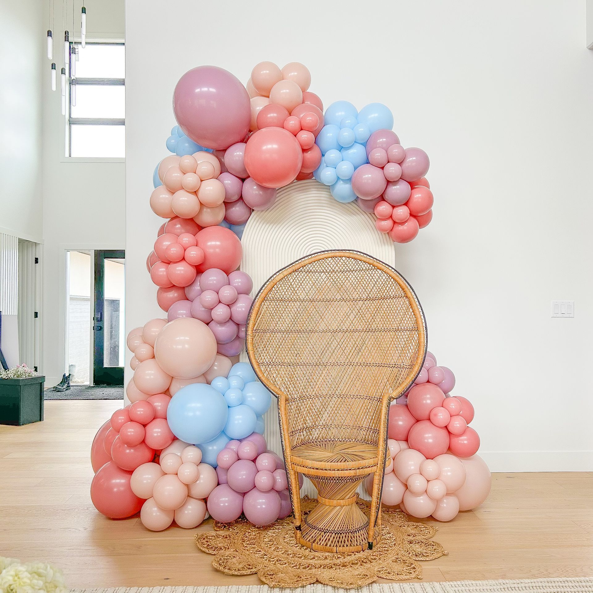 A wicker chair is sitting in front of a balloon arch.