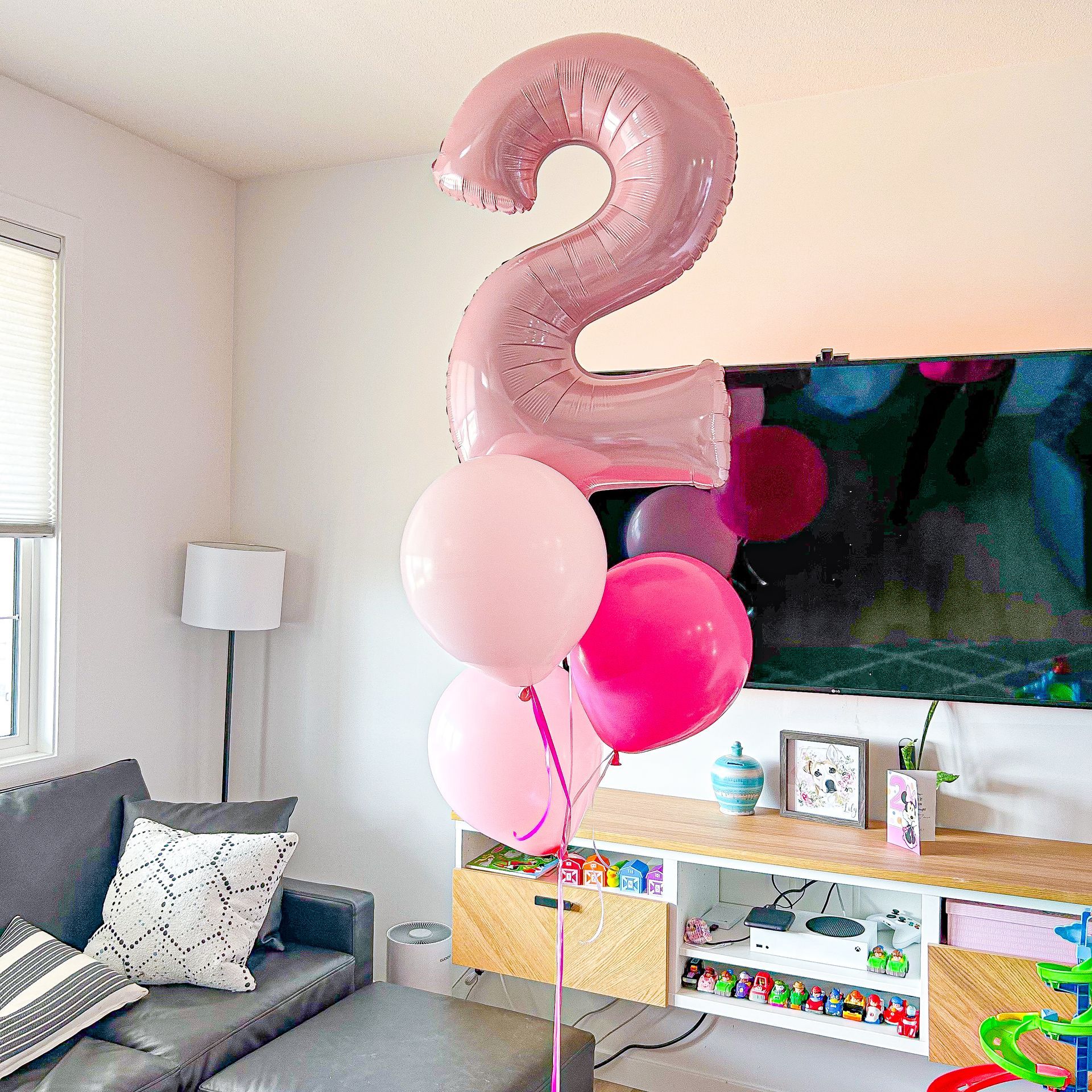A living room with pink balloons and a pink number 2 balloon