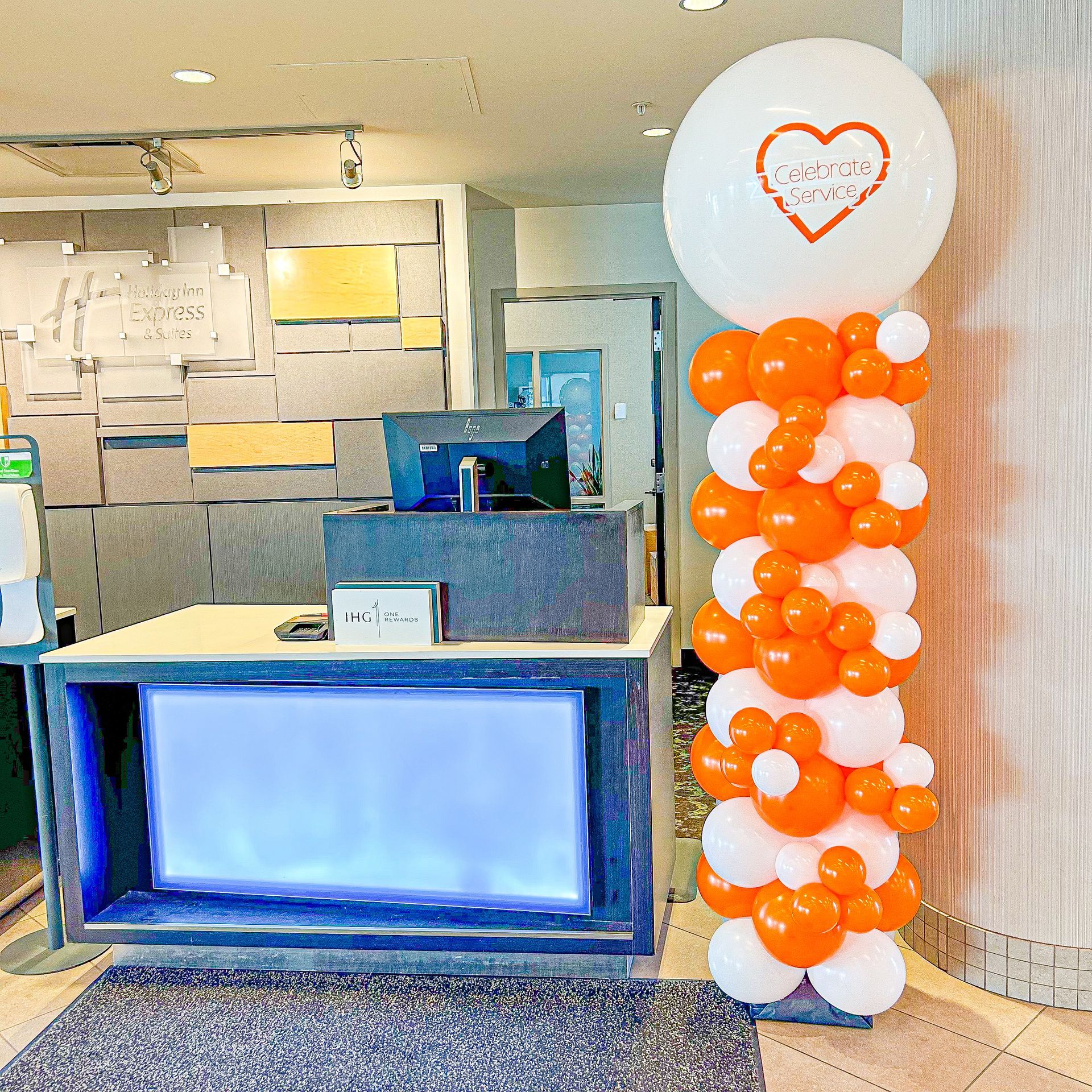 A white balloon with a heart on it is surrounded by orange and white balloons