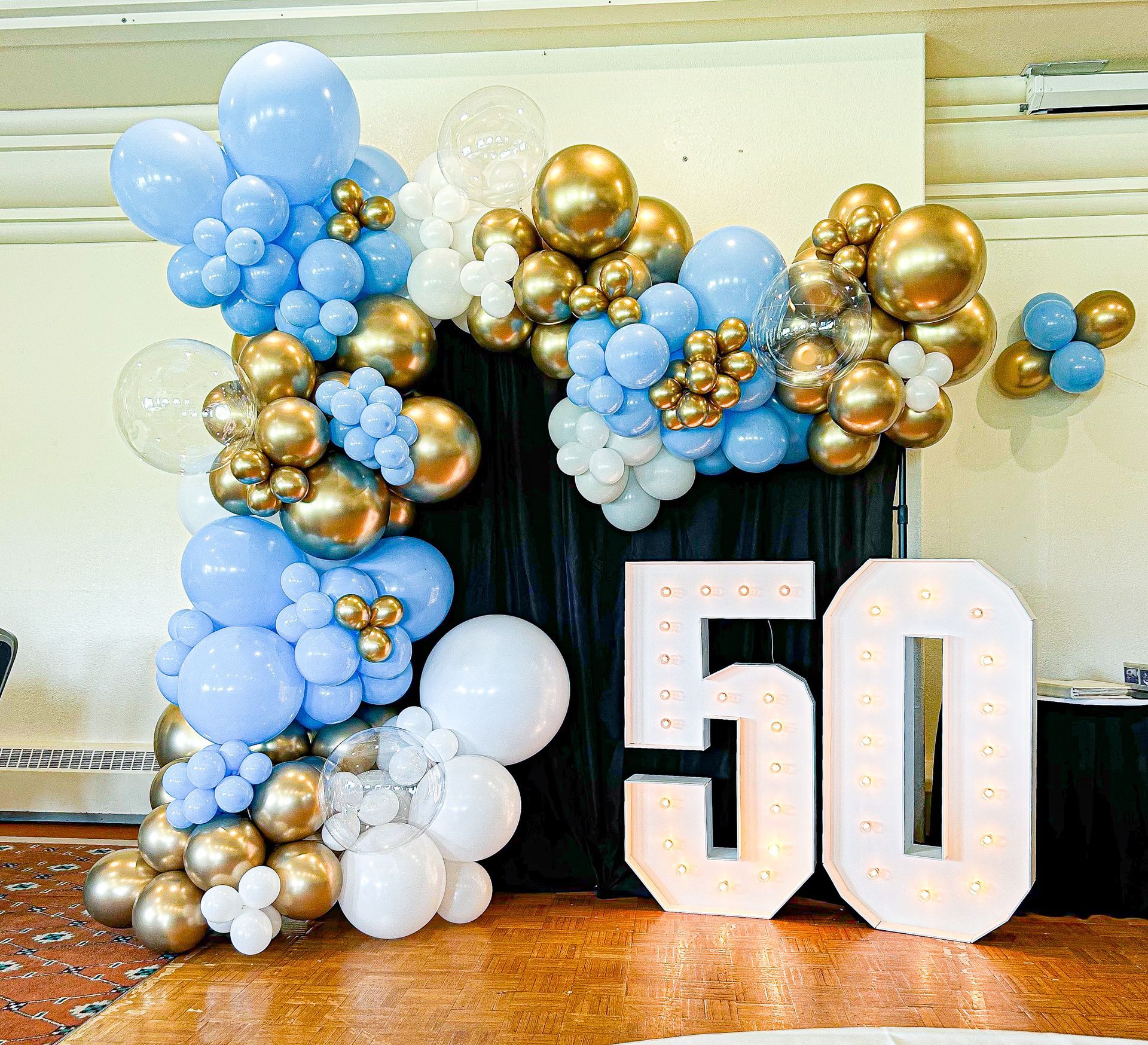 A large number 50 is surrounded by blue and gold balloons.