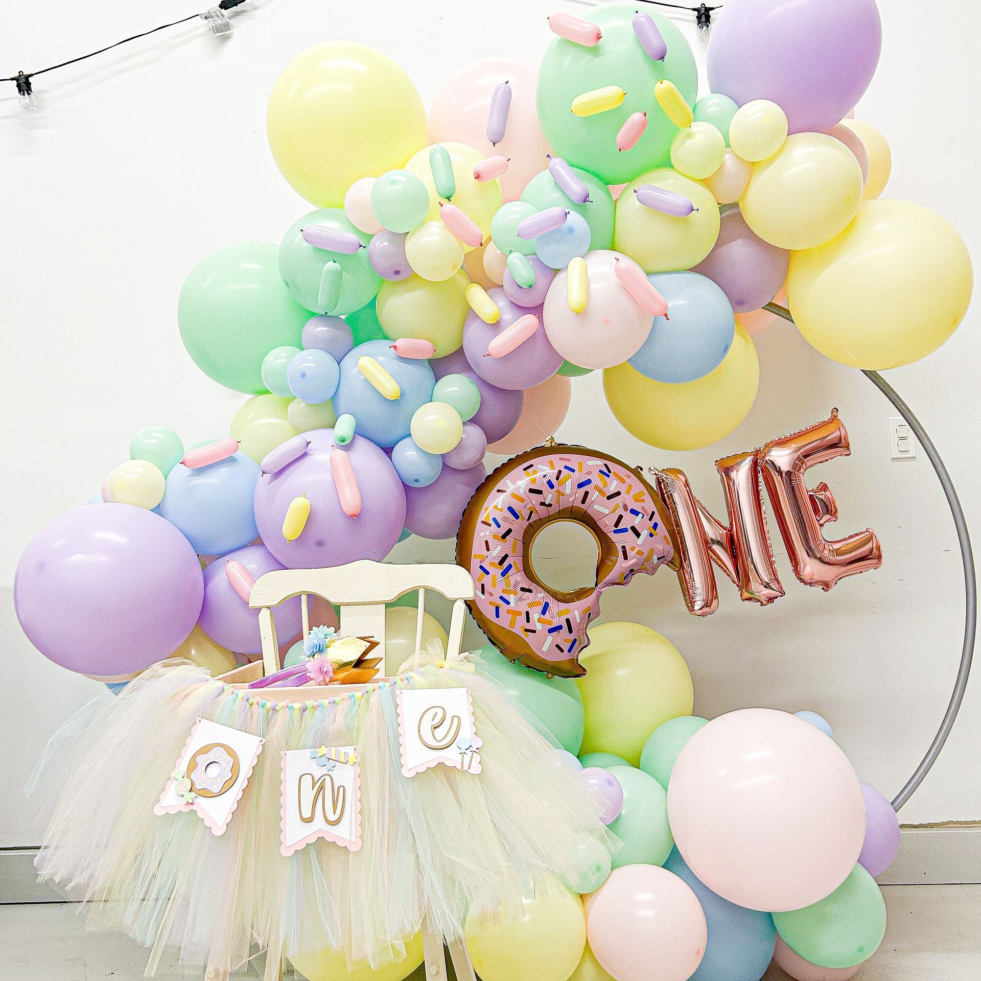 A first birthday decoration with balloons and a donut