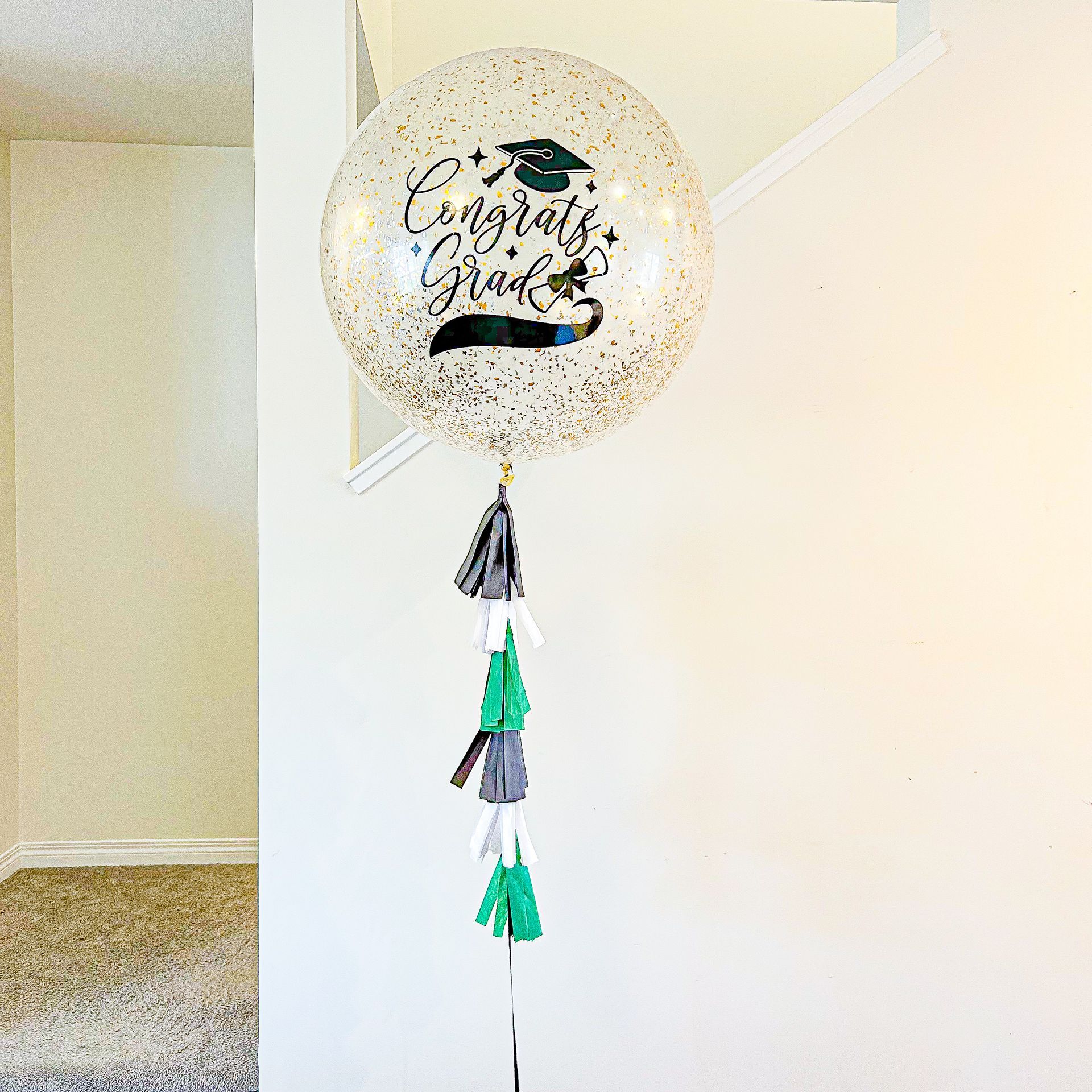 A large congratulations graduation balloon is sitting on a stand in a room.