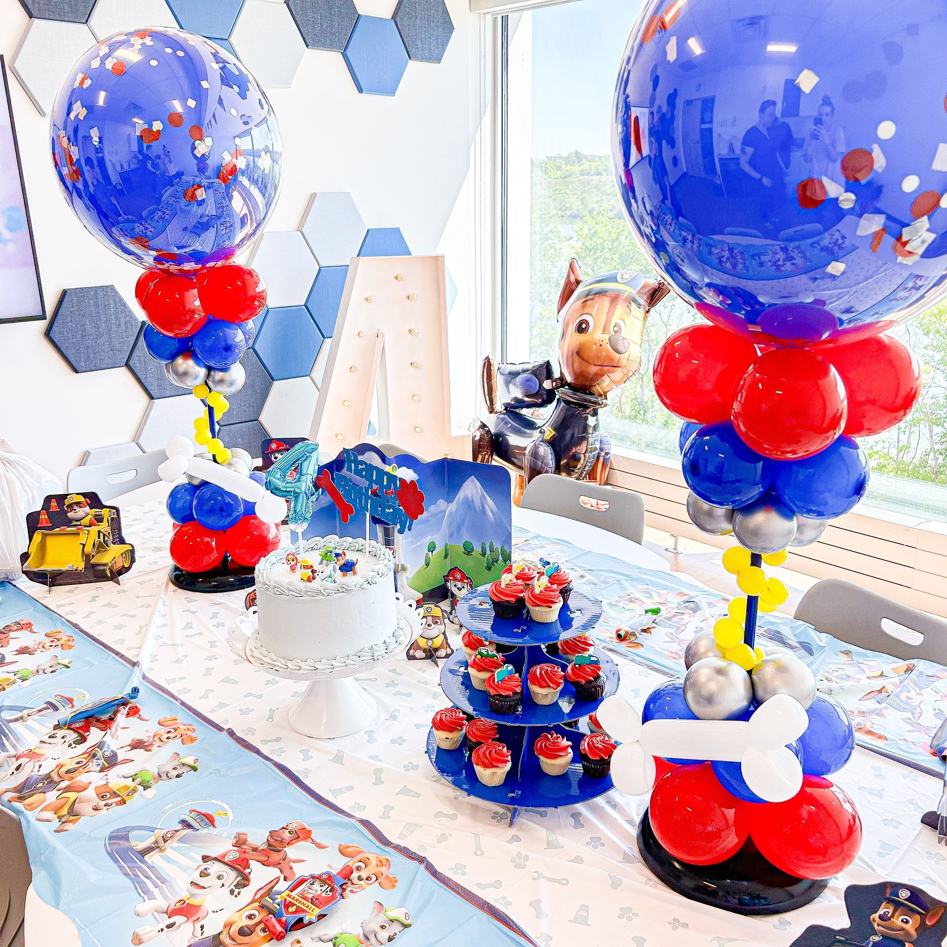 A table decorated with balloons and cupcakes for a paw patrol birthday party.