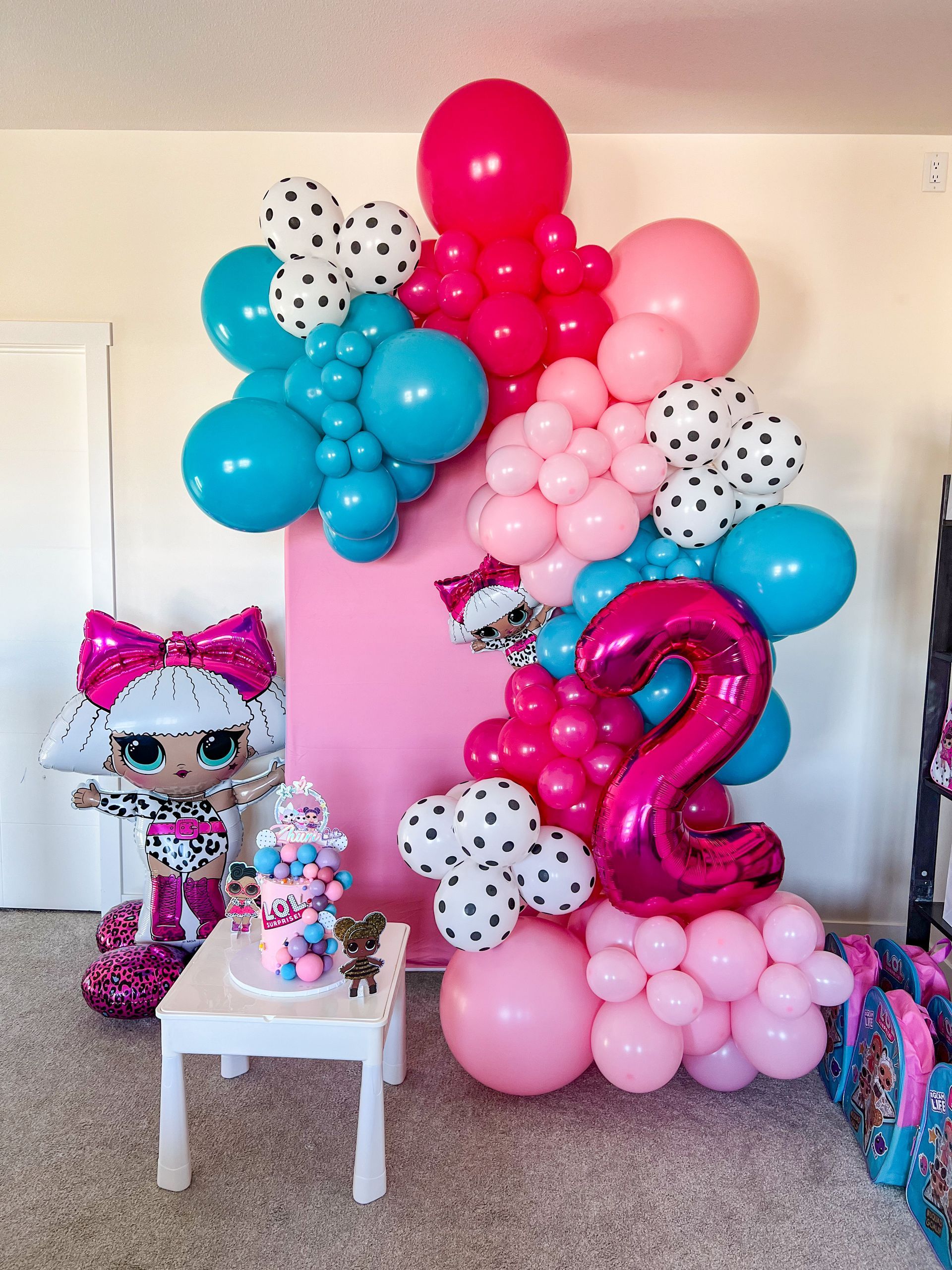 A room filled with balloons and a cake on a table.