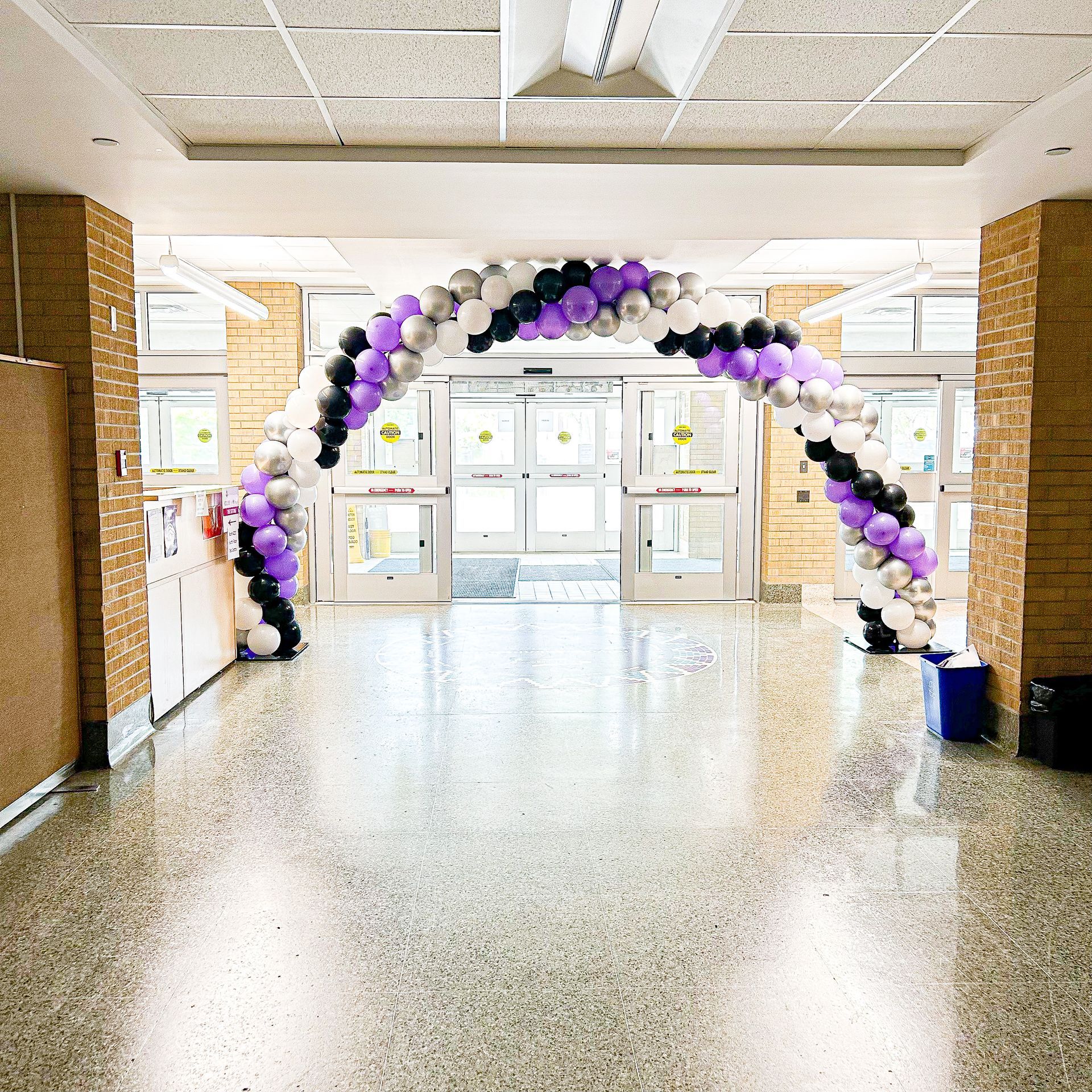 A hallway with a purple and black balloon arch