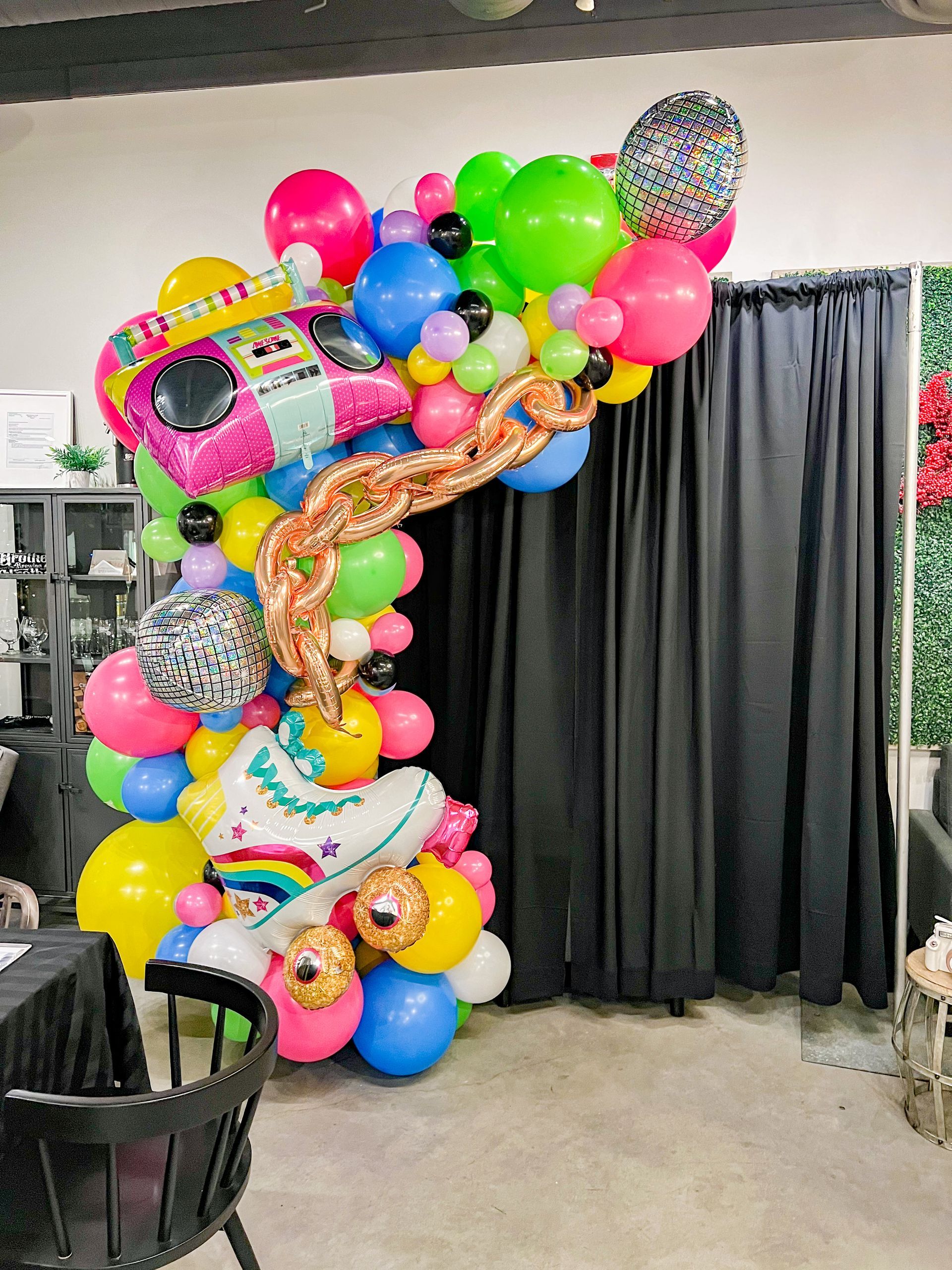 A room filled with lots of colorful balloons and a black curtain.