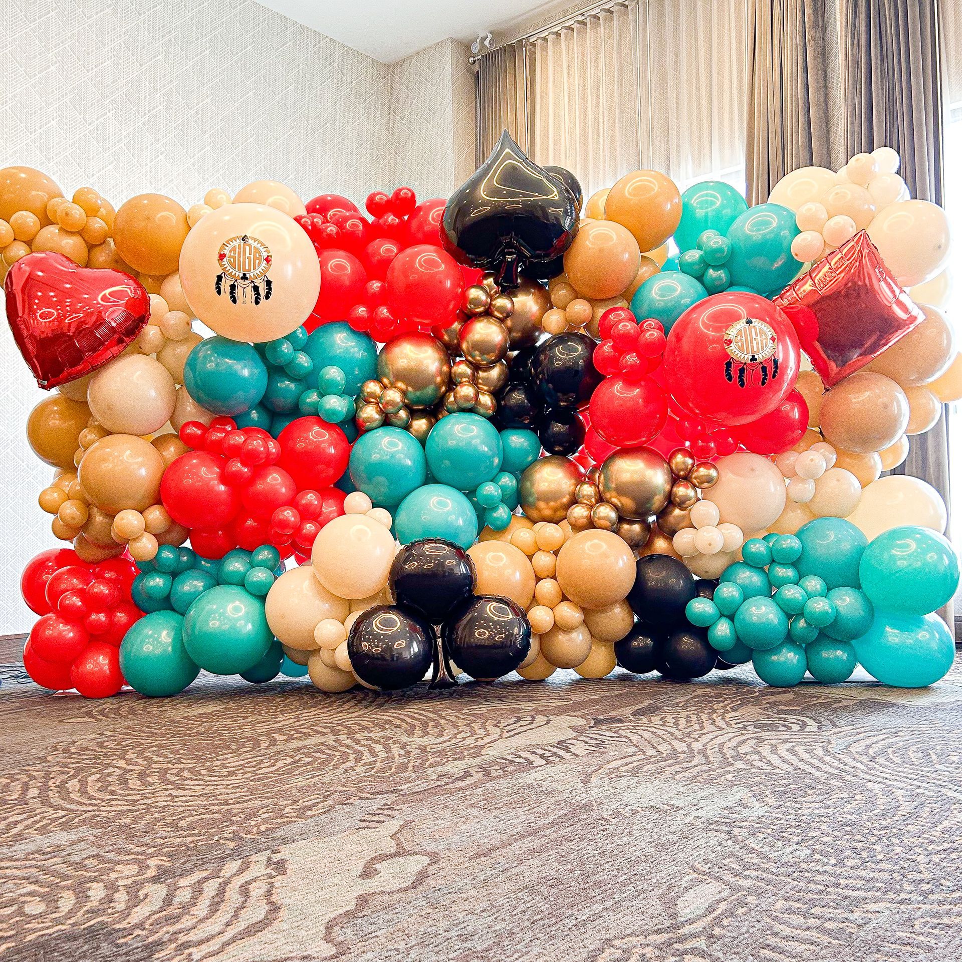 A wall filled with lots of colorful balloons in a room.