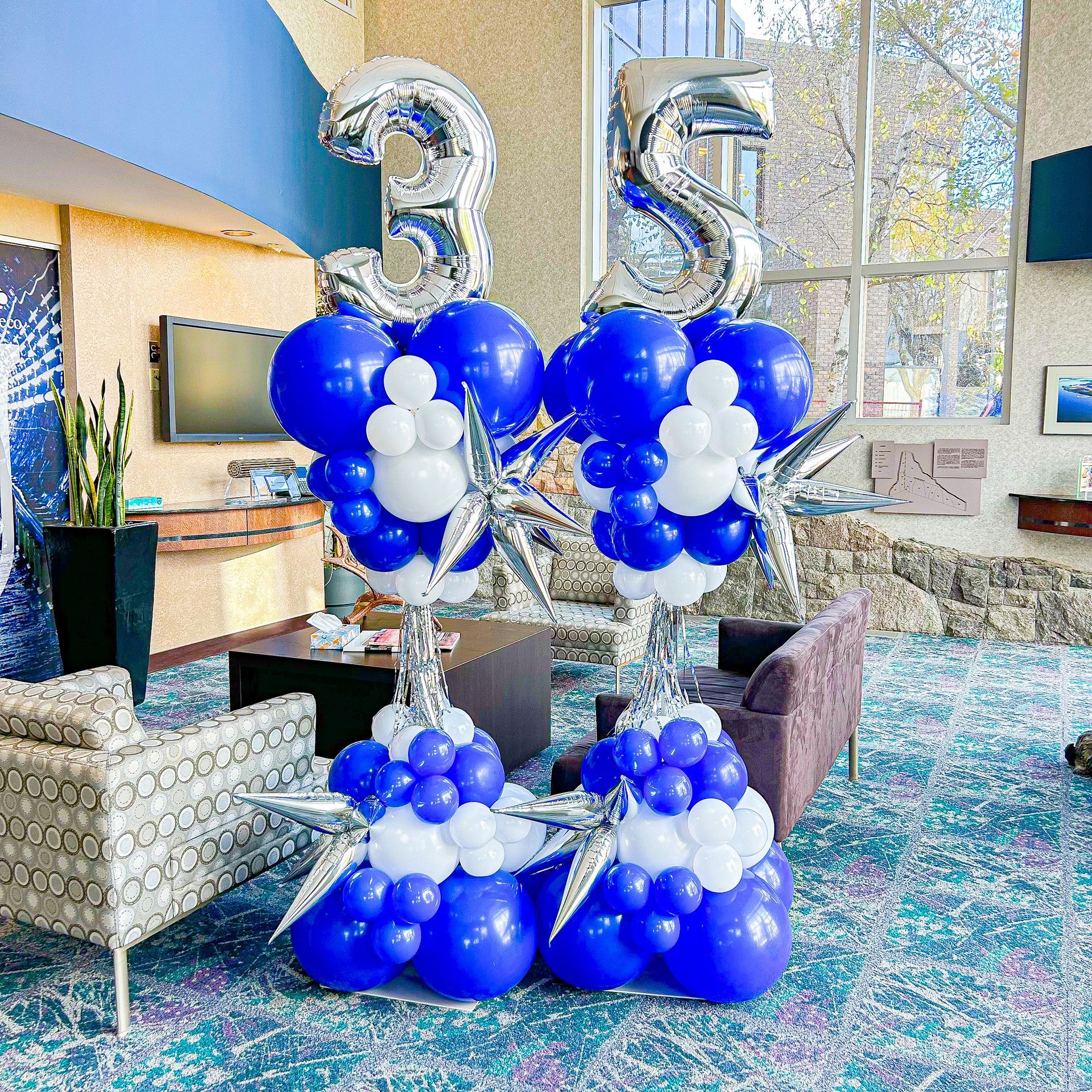A room decorated with blue and white balloons and silver balloons.