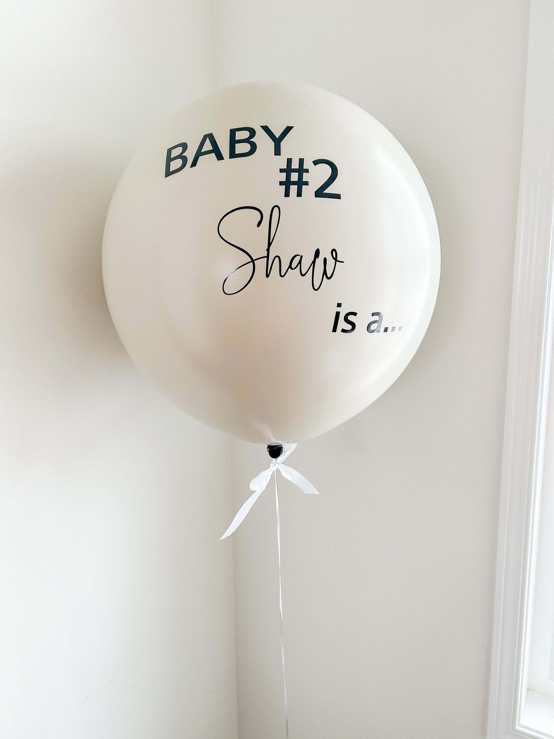 A white balloon that says baby # 2 shaw is a