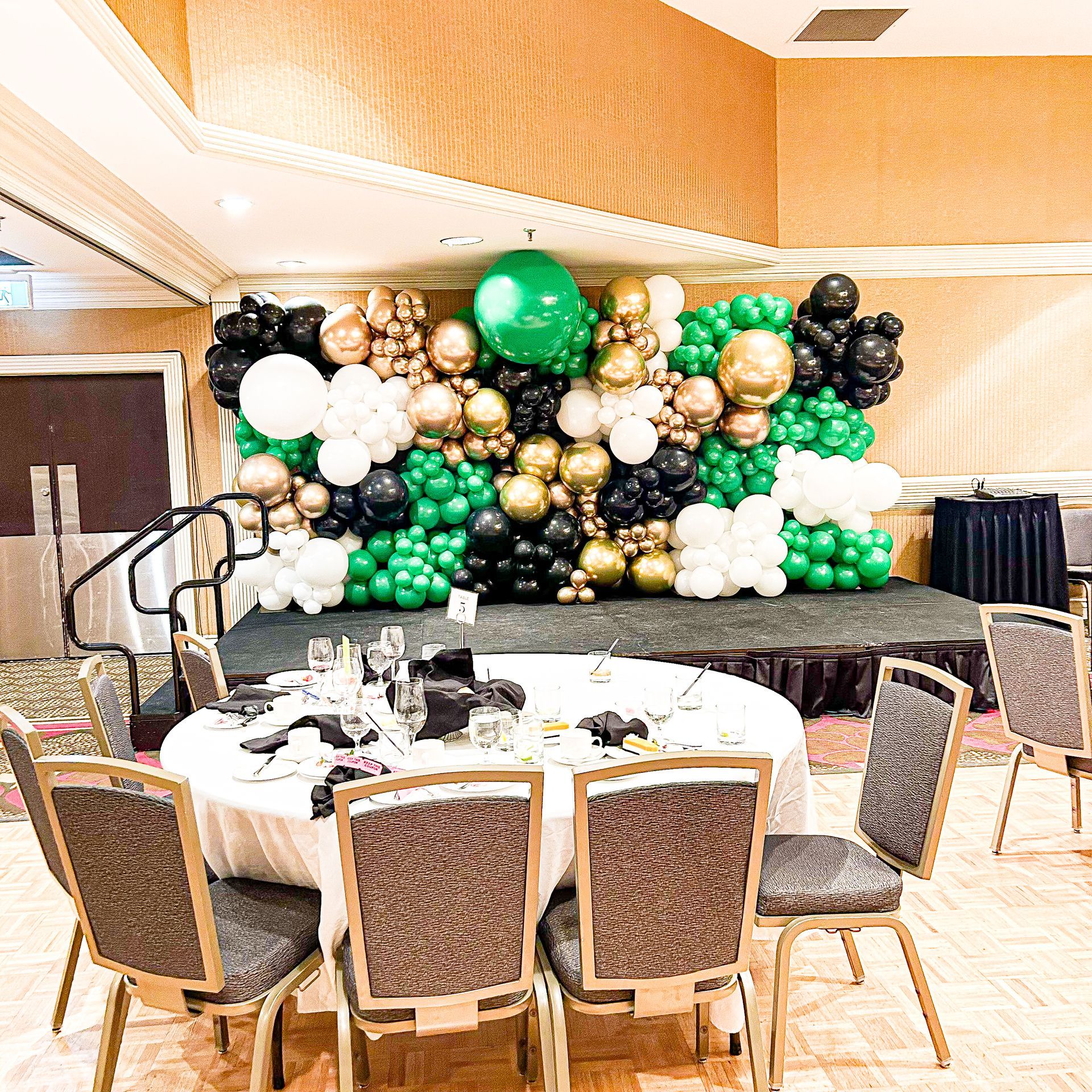 A room with tables and chairs and a wall of balloons