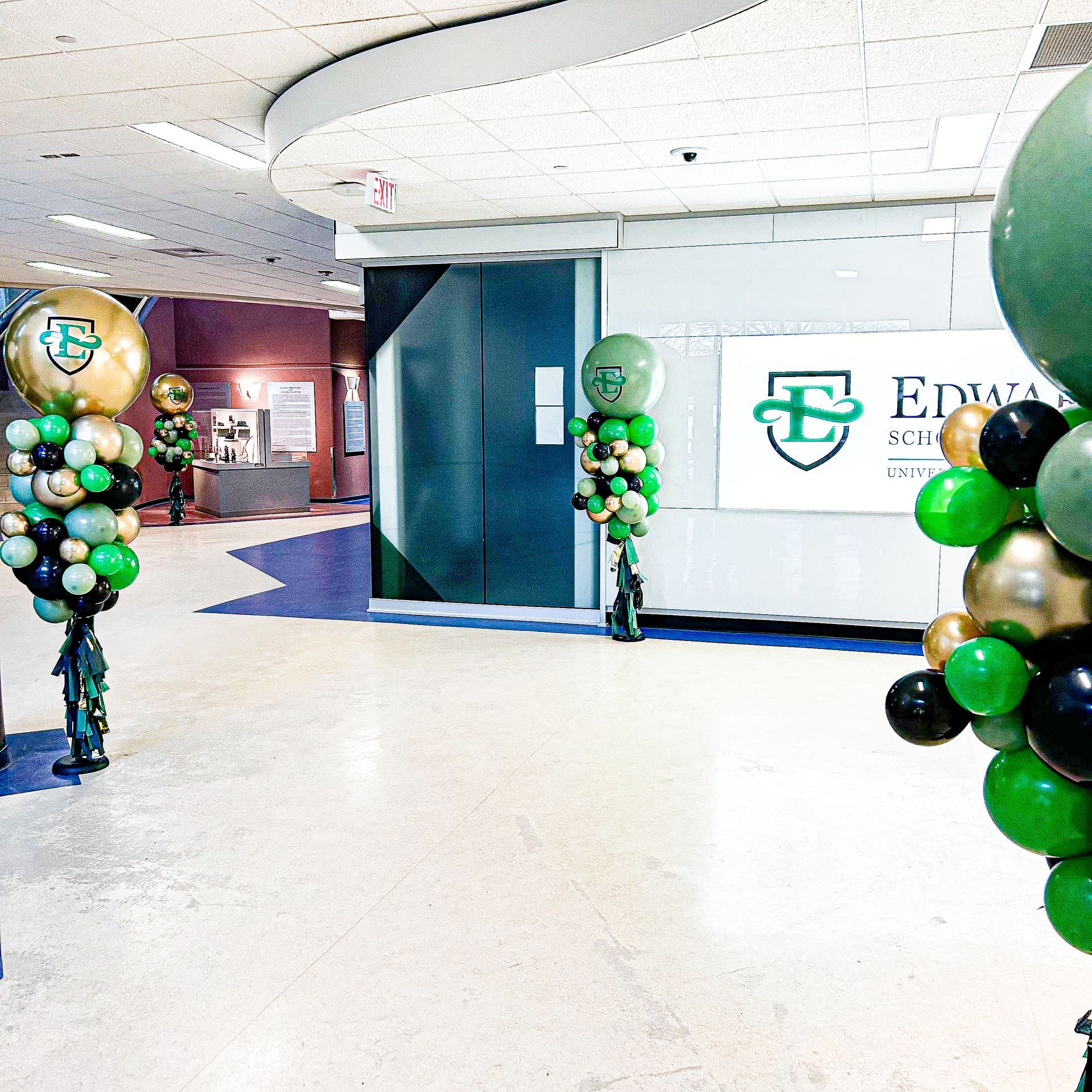 Green and gold balloons in front of a sign that says edwards