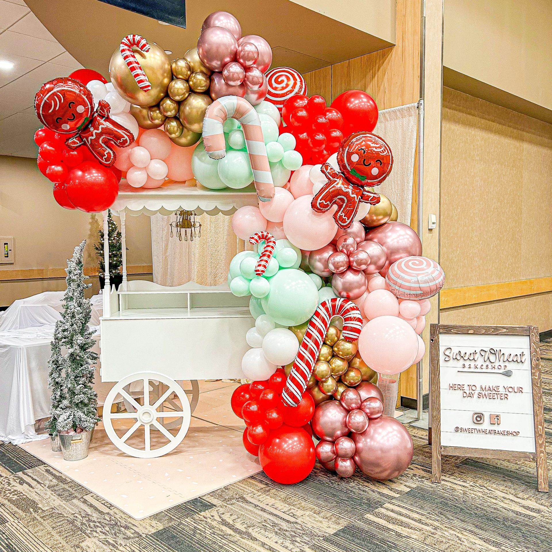 A candy cart is decorated with balloons and candy canes.