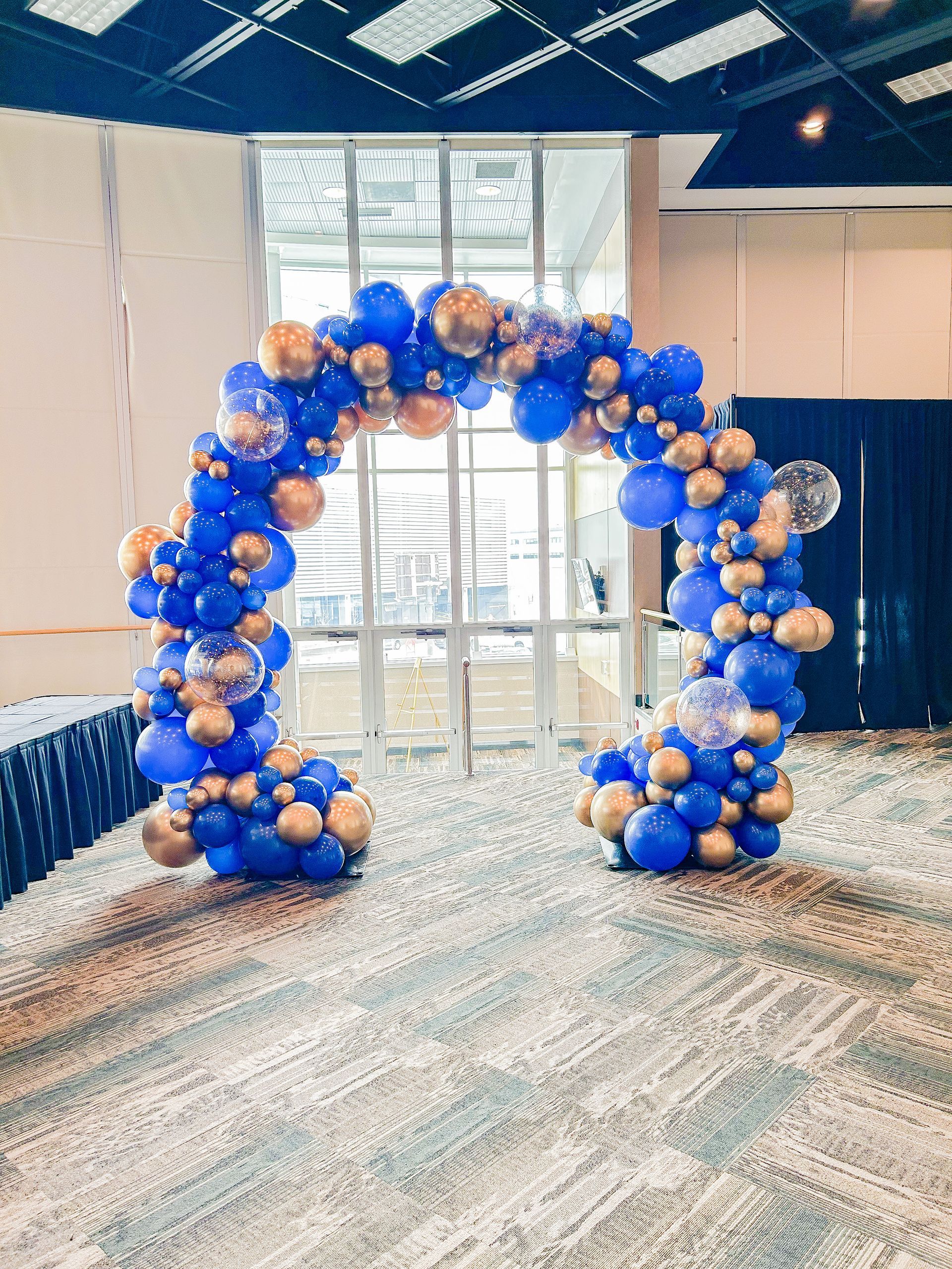 A large arch made of blue and gold balloons in a room.