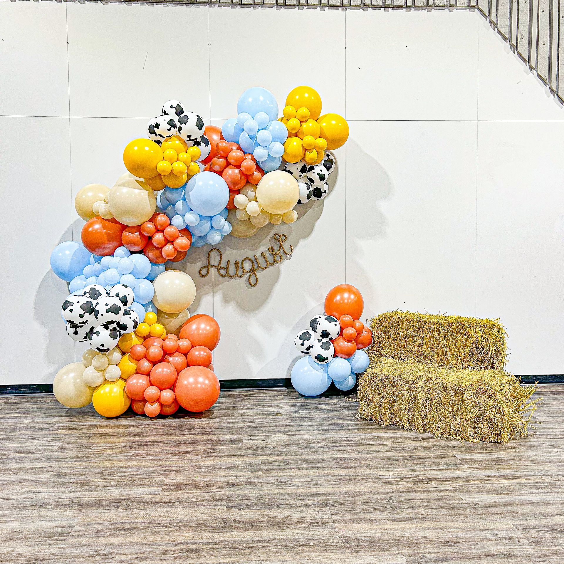 A wall decorated with balloons and hay bales.