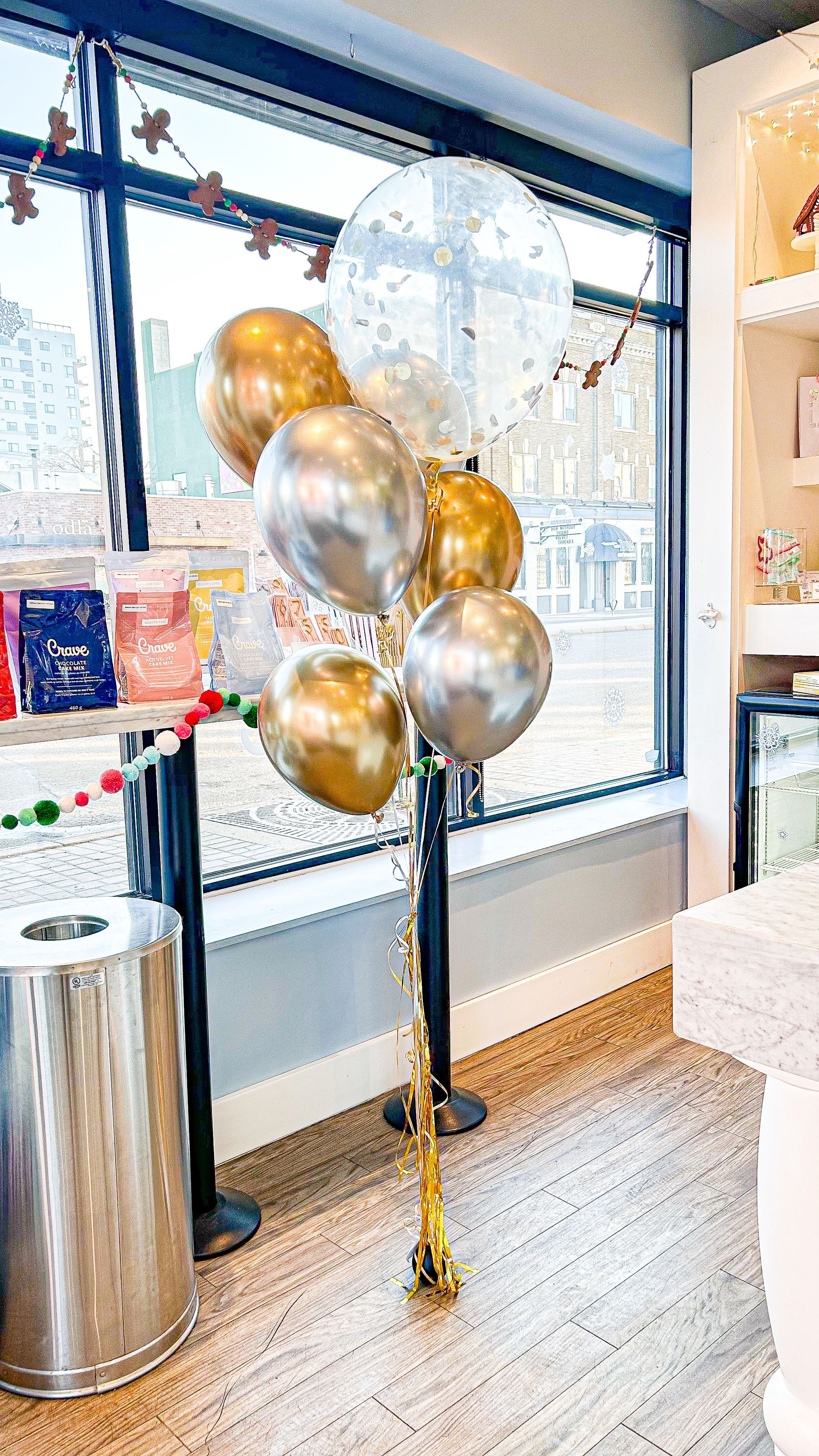 A bunch of gold and silver balloons are sitting in front of a window in a room.