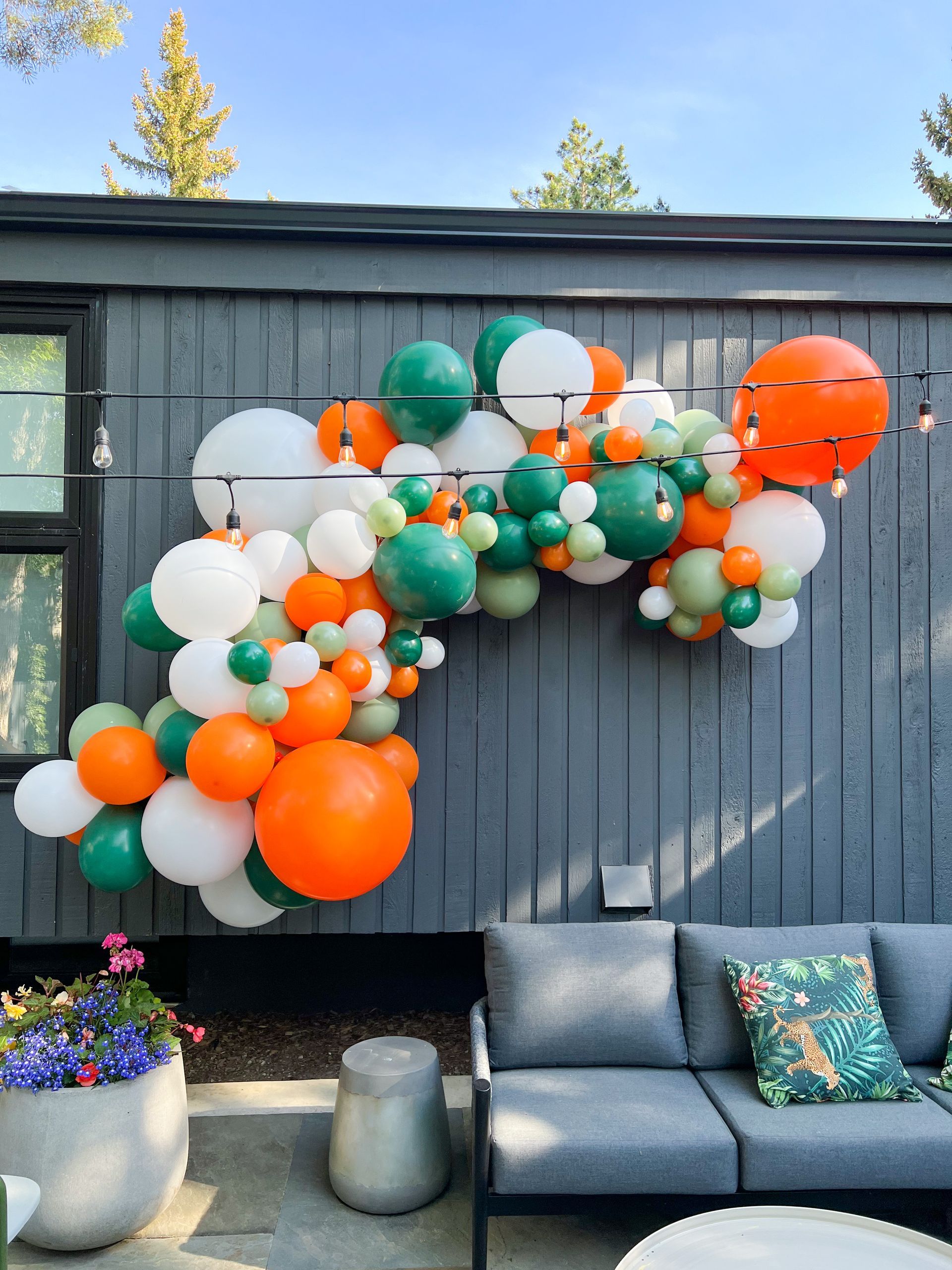 A bunch of balloons are hanging on a wall next to a couch.