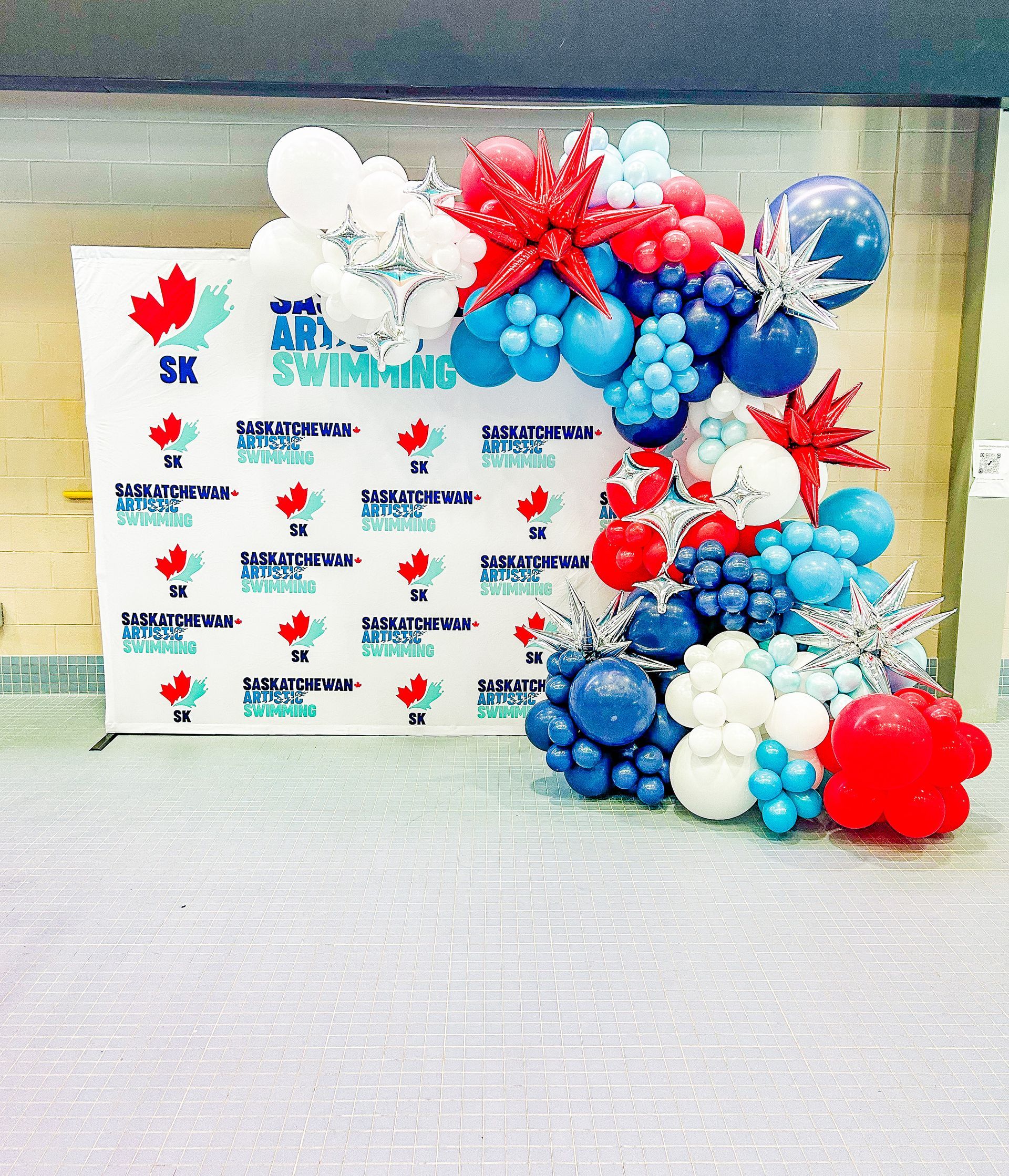 A wall covered in red , white and blue balloons.