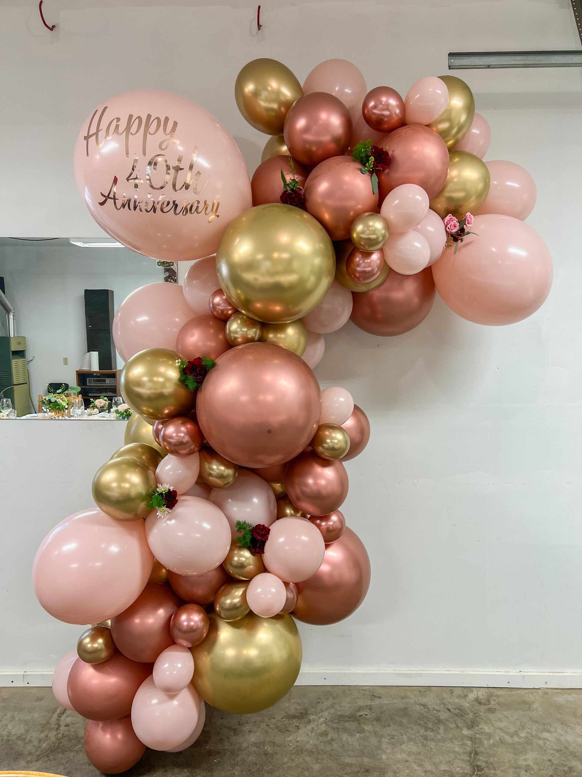 A bunch of pink and gold balloons are hanging on a wall.