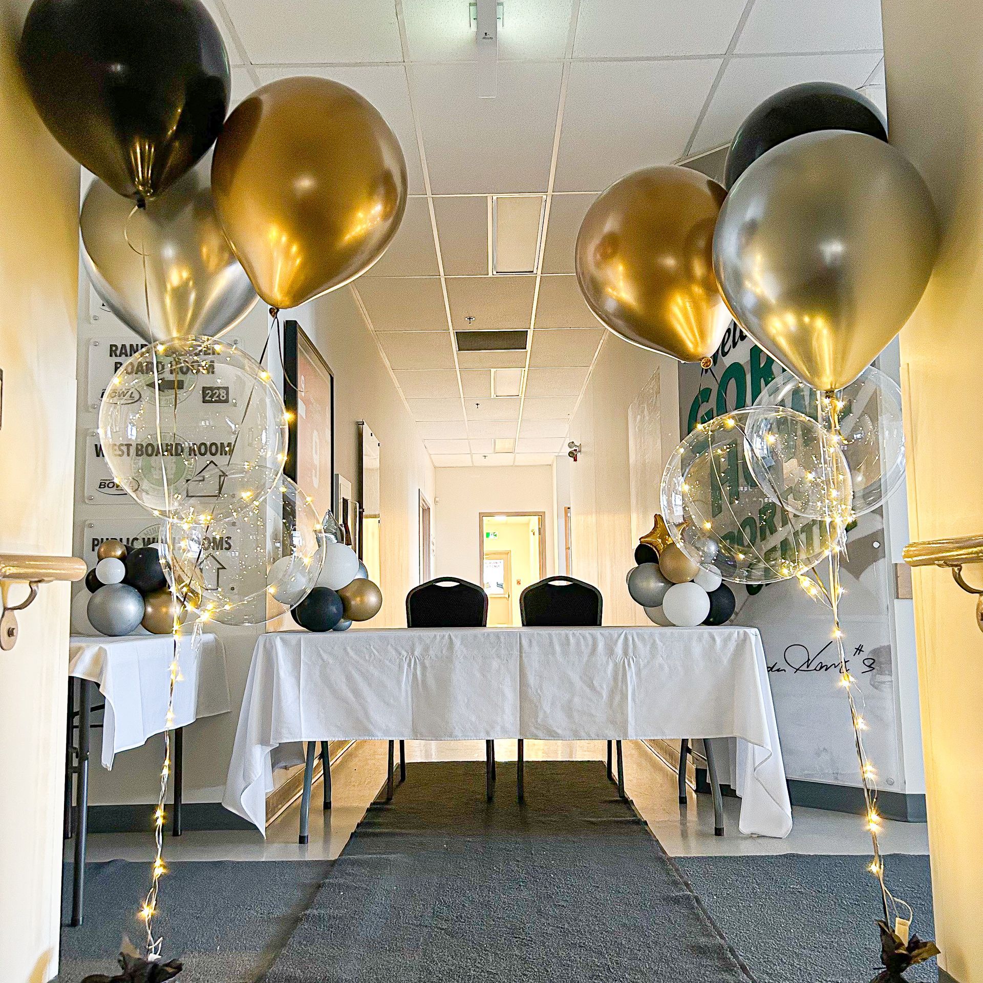A hallway is decorated with balloons and a table