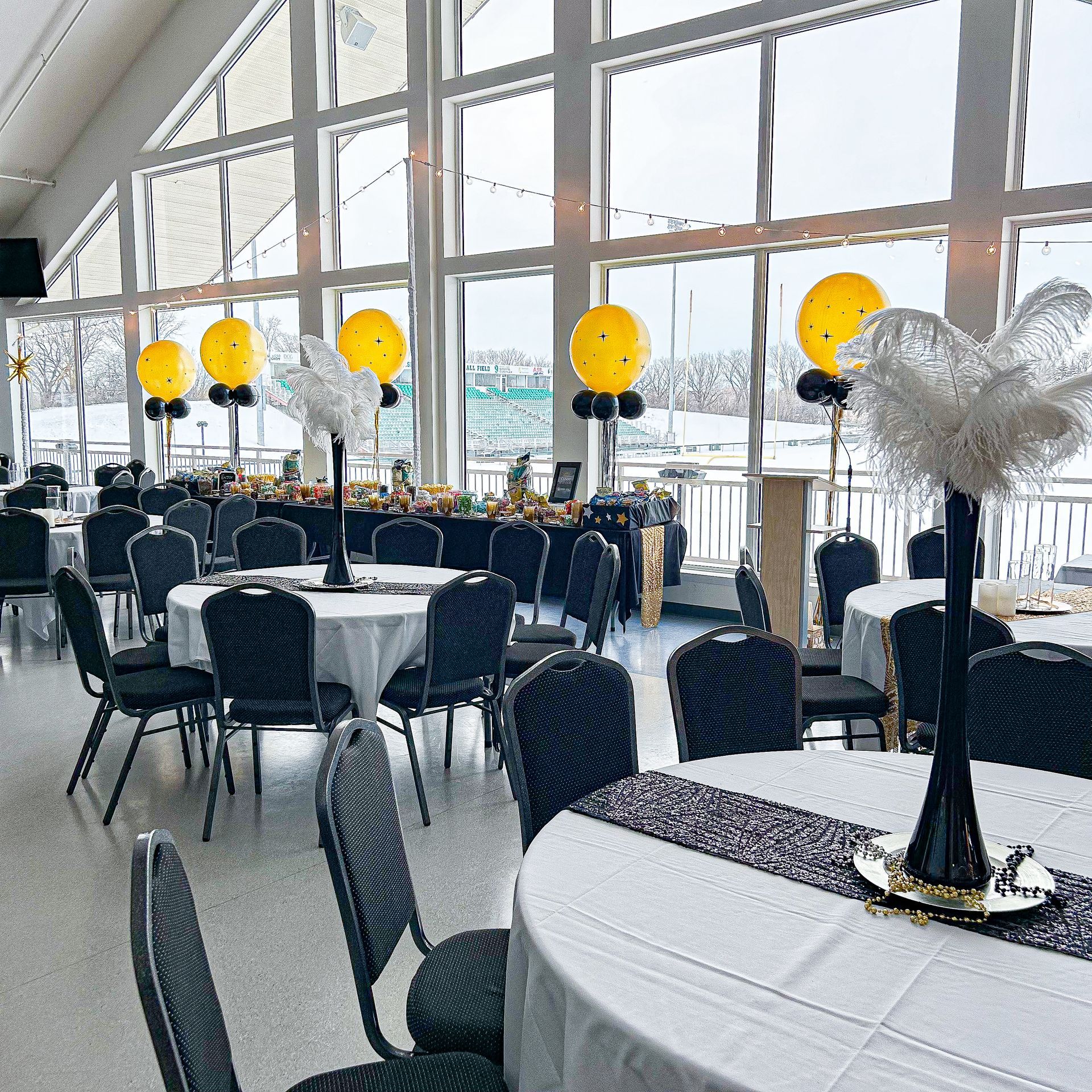 A large room with tables and chairs and yellow balloons