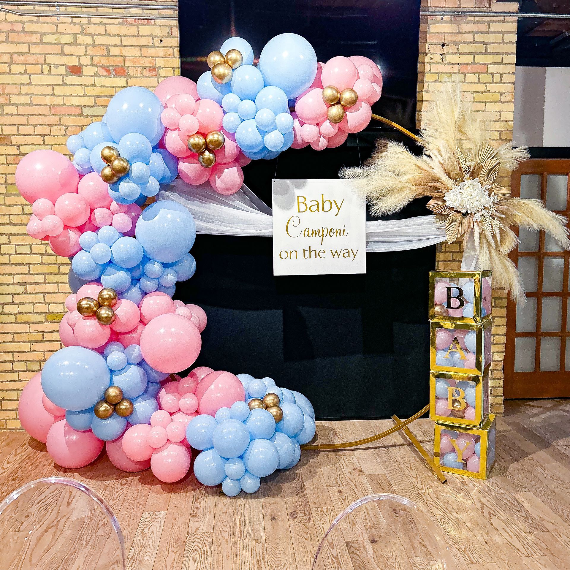 A baby shower with pink and blue balloons and a sign that says baby comes on the way