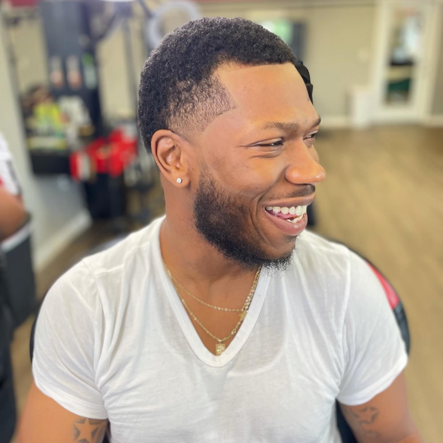 A man with a beard is wearing a white shirt and smiling.