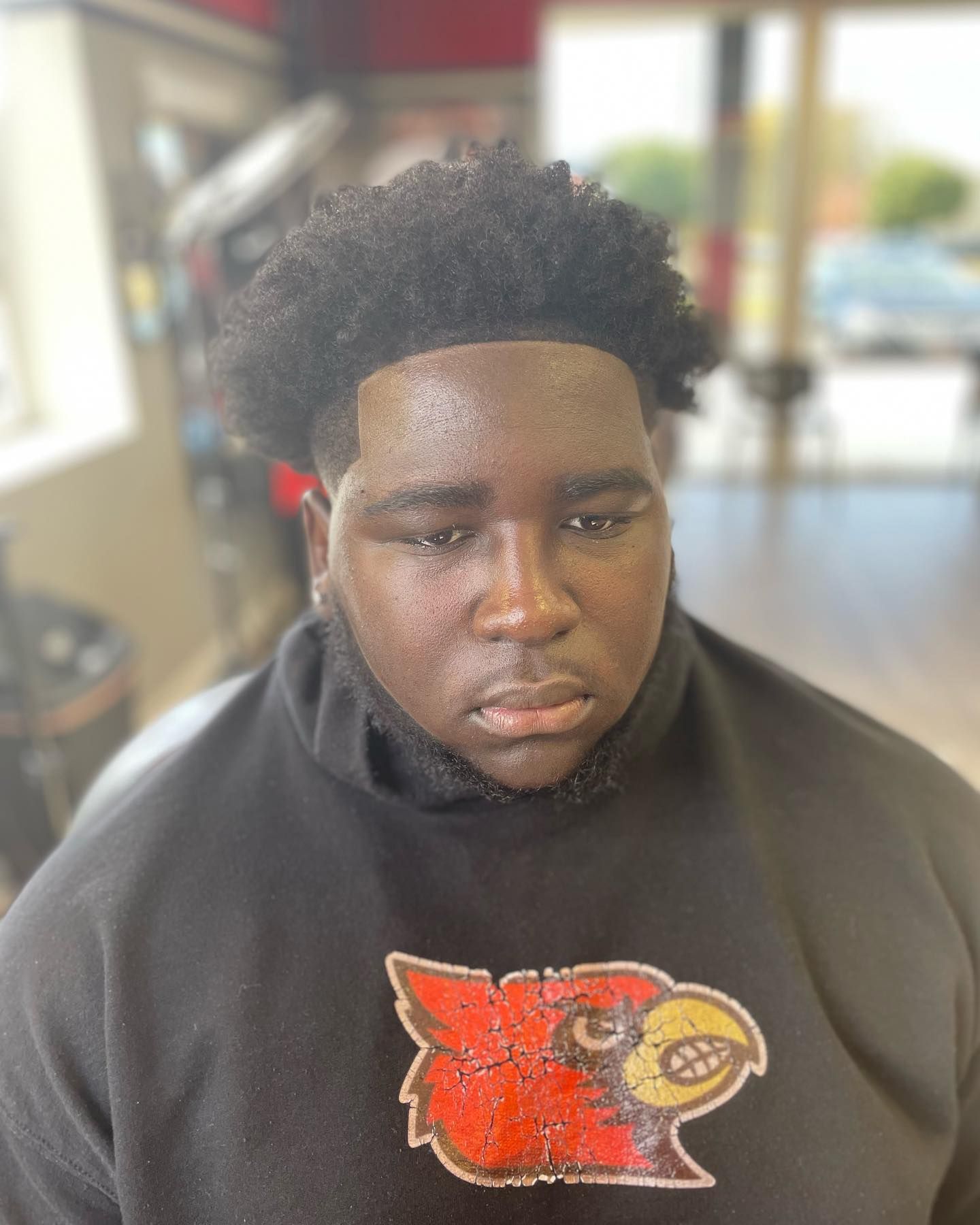 A man wearing a black sweatshirt with a bird on it.