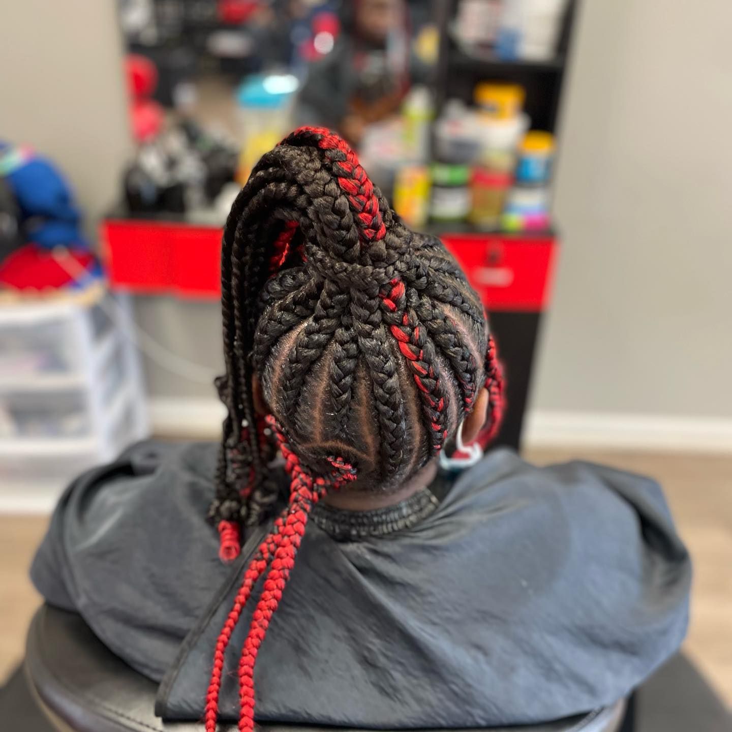 A woman is sitting in a chair with braids in her hair.
