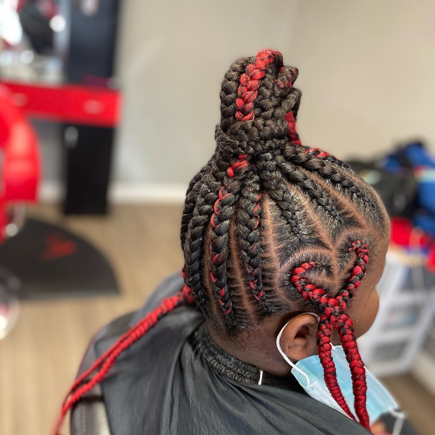 A woman with red braids in a bun is wearing a mask.