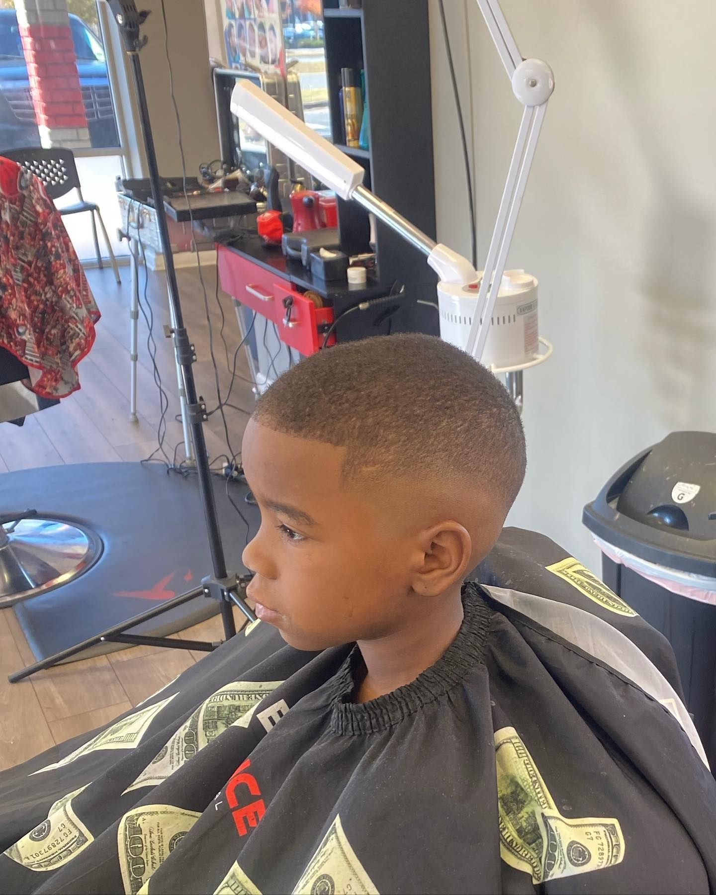 A young boy is getting his hair cut at a barber shop.
