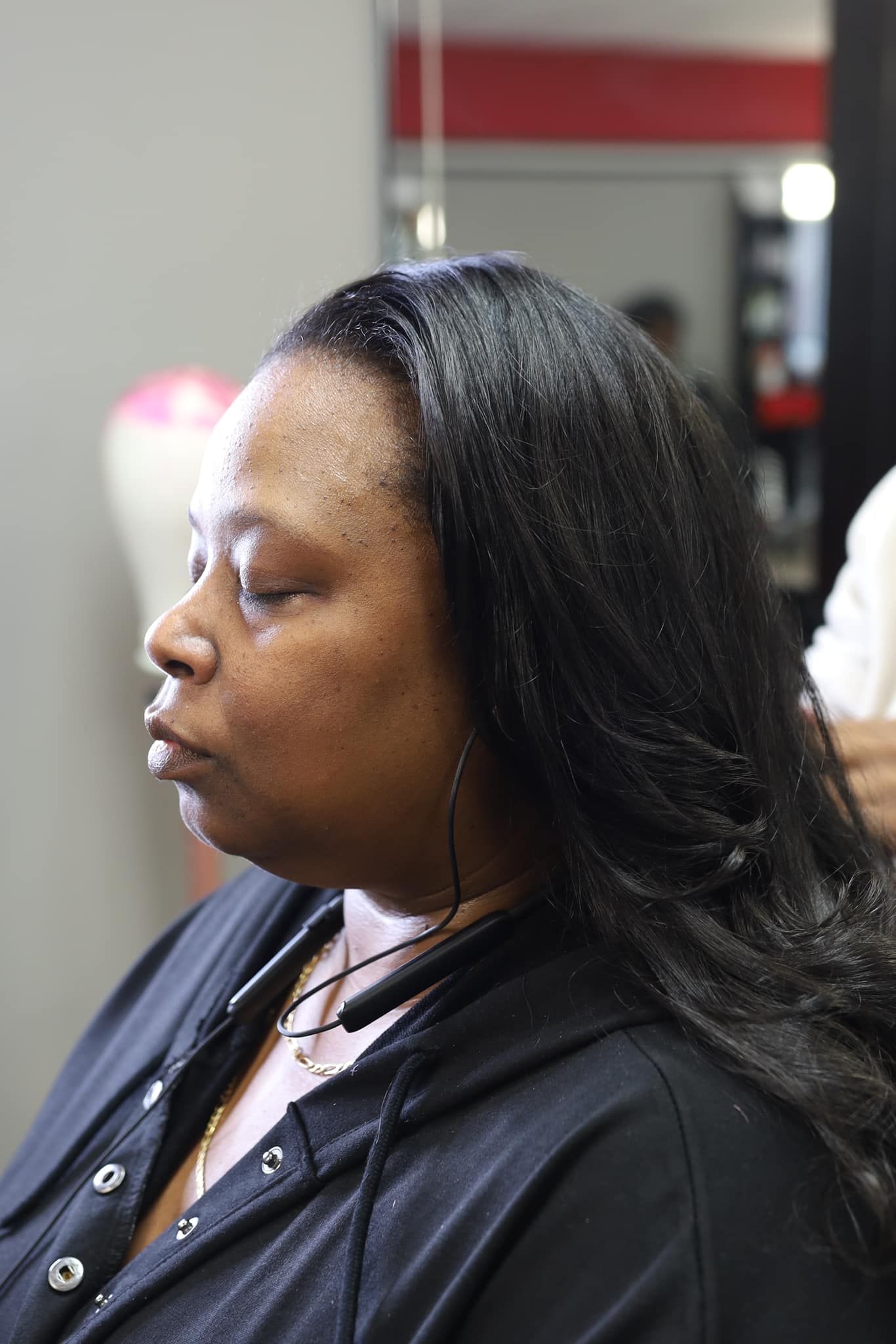 A woman is getting her hair cut at a salon.
