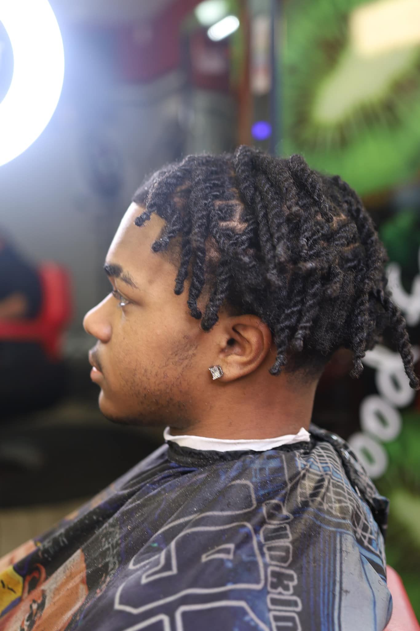 A young man is getting his hair cut at a barber shop.