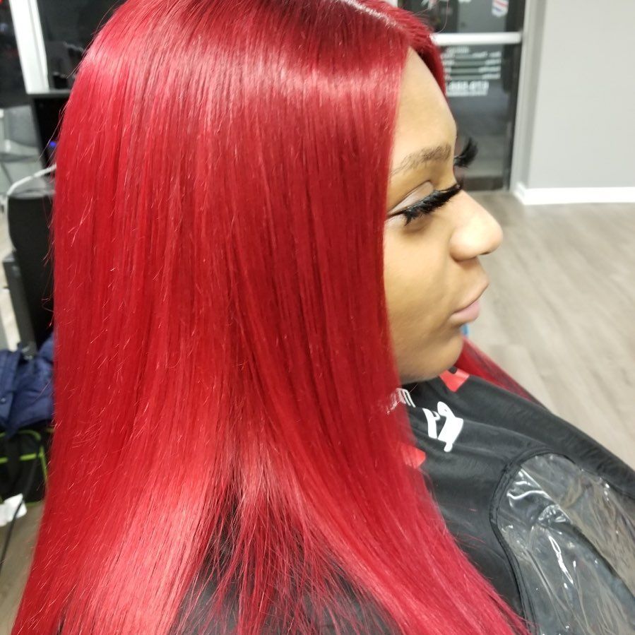 A woman with long red hair is sitting in a chair in a salon.
