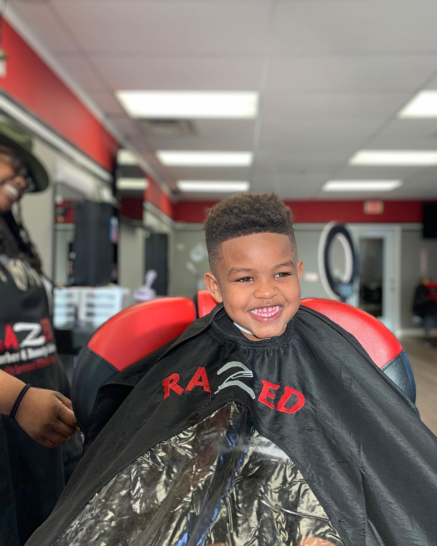 A young boy is getting his hair cut at a barber shop.