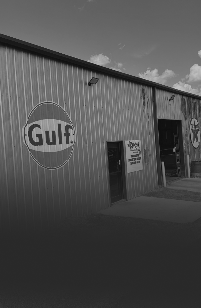 A black and white image of a metal industrial building with a Gulf Oil logo on the wall and several open service bays. | Rapid Auto and Truck Repair