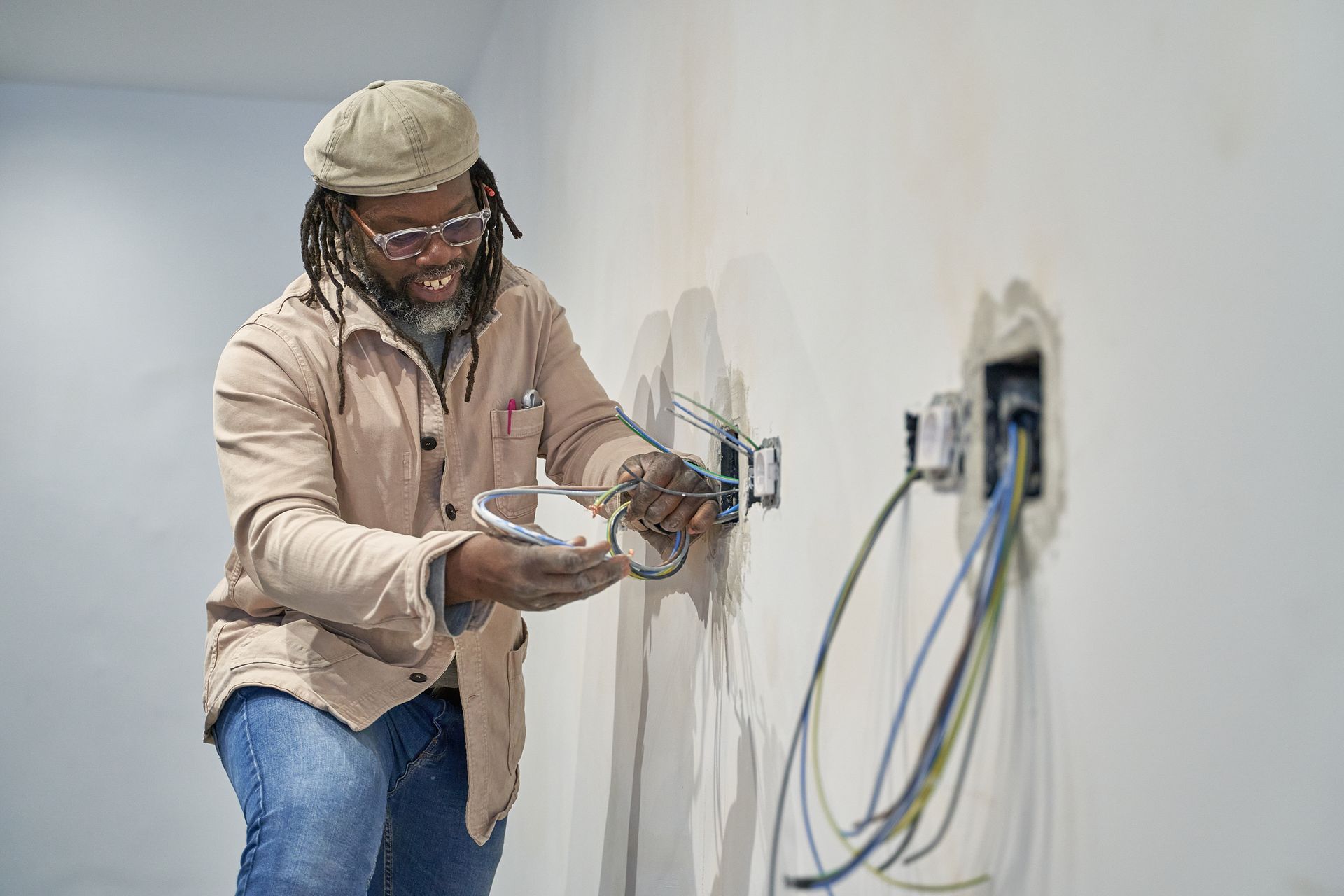 A man is working on an electrical outlet on a wall.