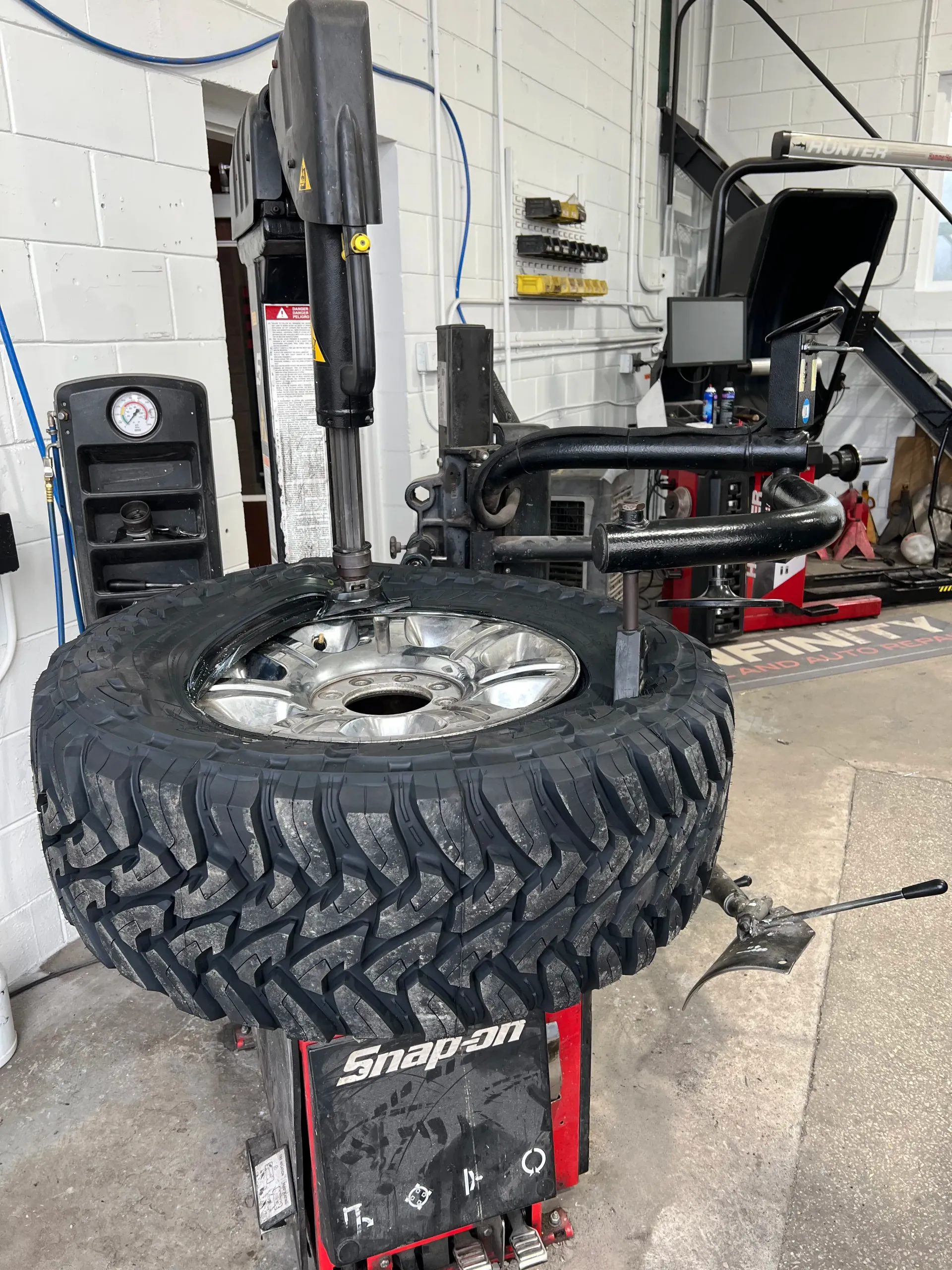 A large, off-road tire mounted on a Snap-on tire changing machine | Infinity Tires and Auto Repair
