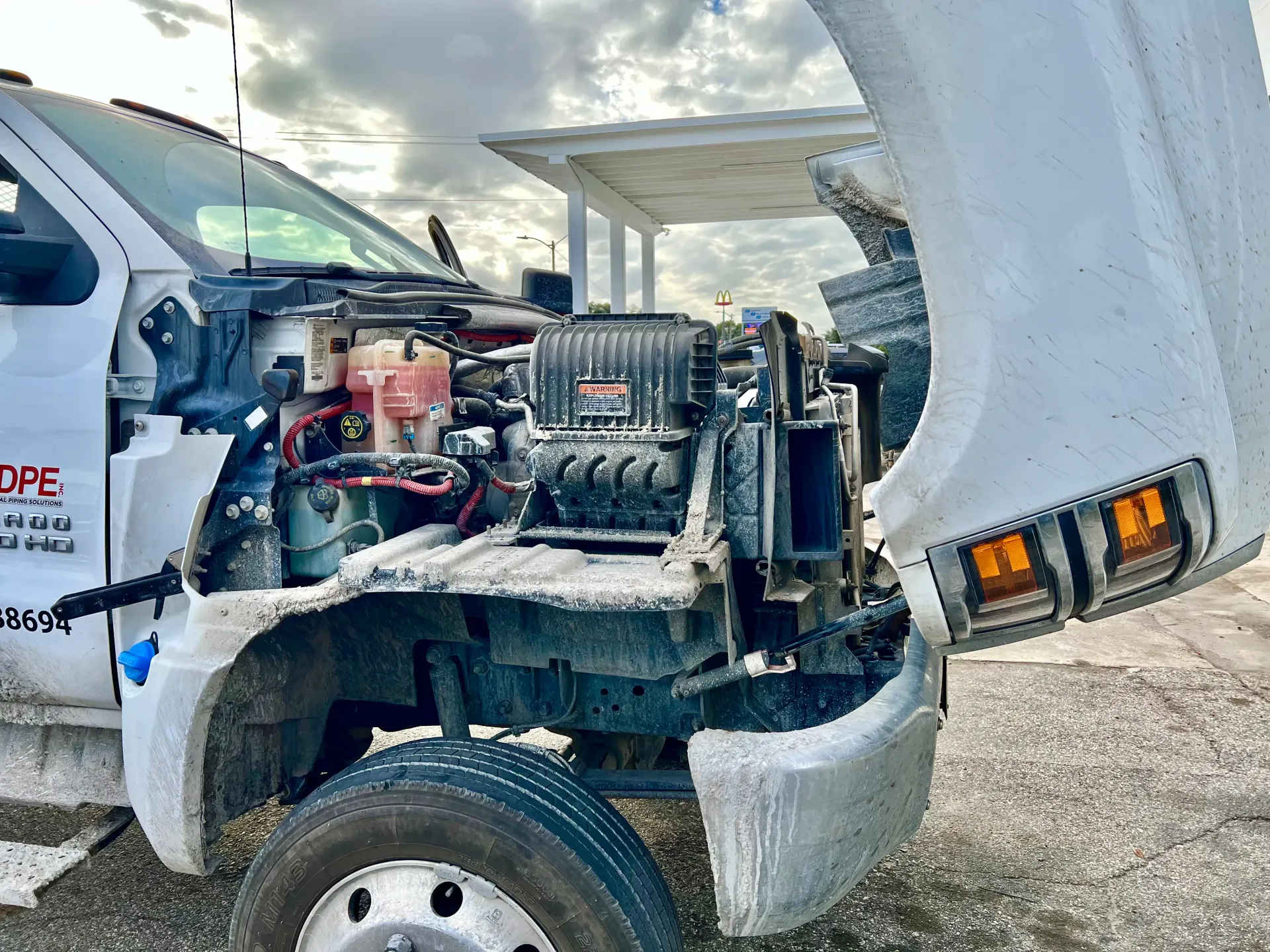 A white work truck with its hood open, revealing the engine components | Infinity Tires and Auto Repair