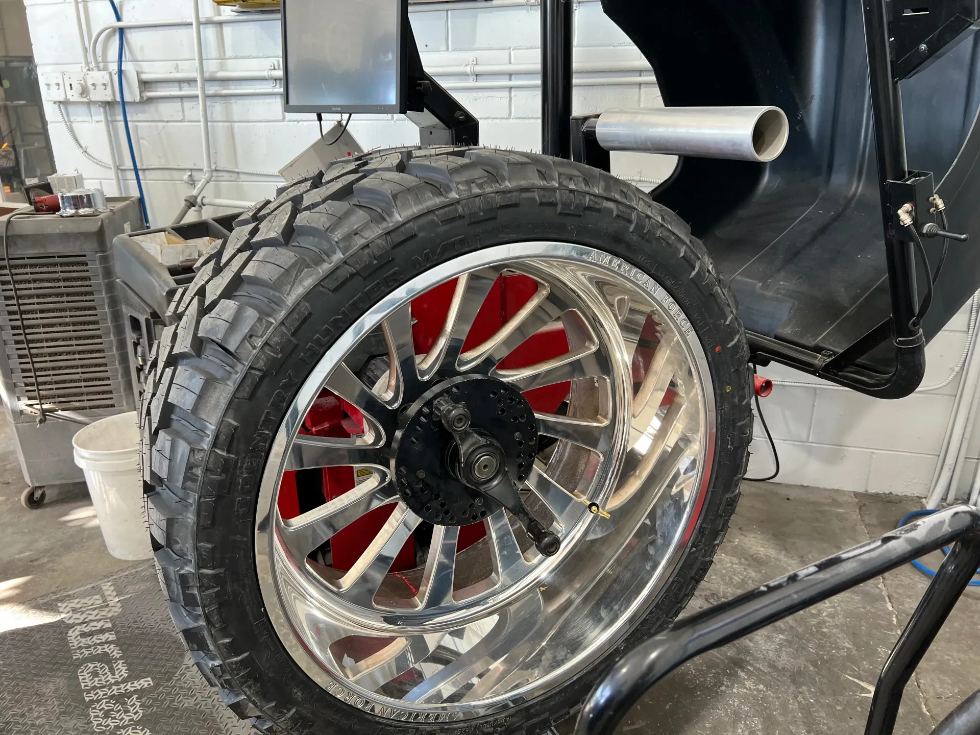A chrome wheel with an off-road tire mounted on a piece of machinery | Infinity Tires and Auto Repair