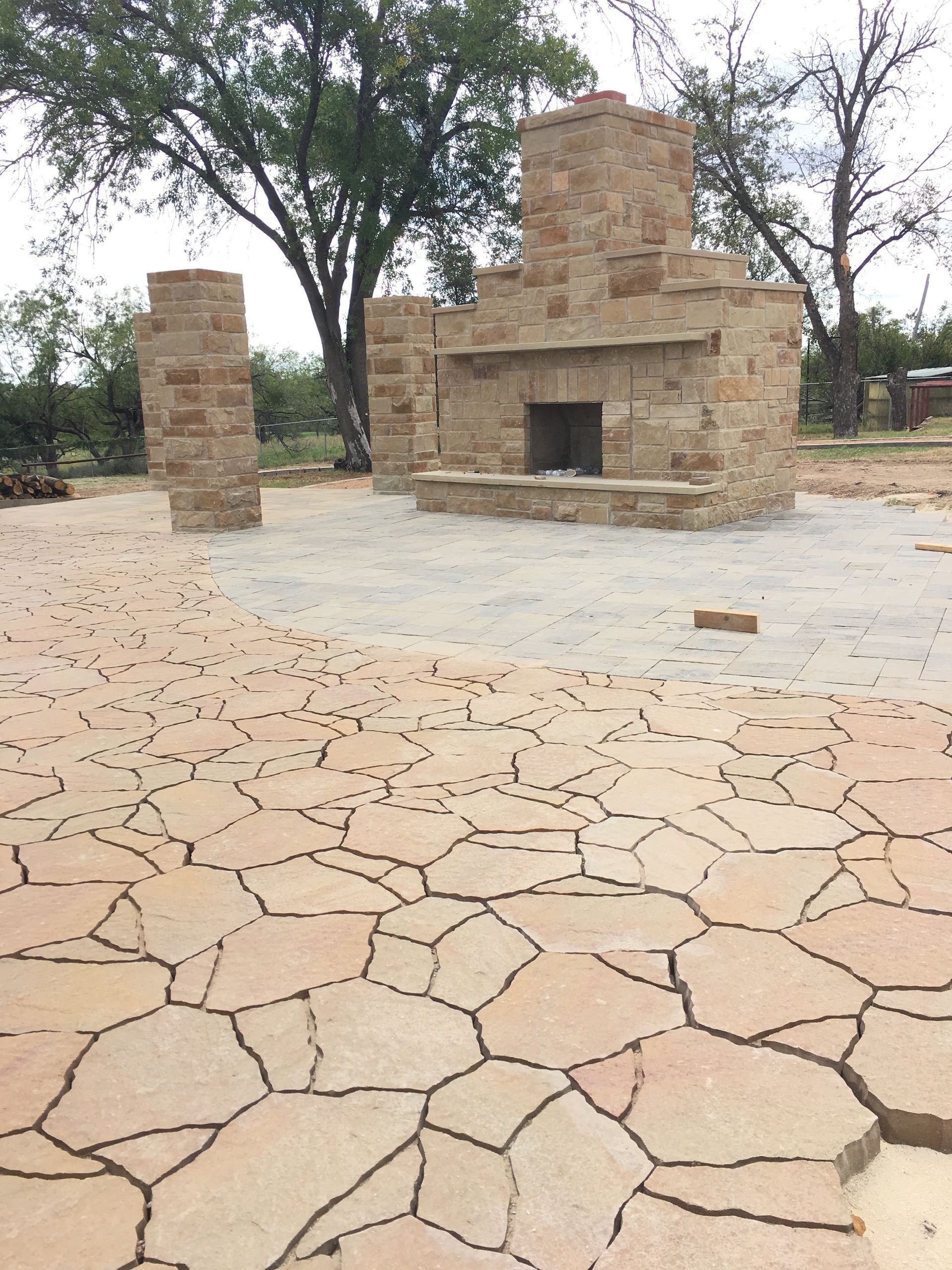 A stone fireplace is sitting in the middle of a patio.