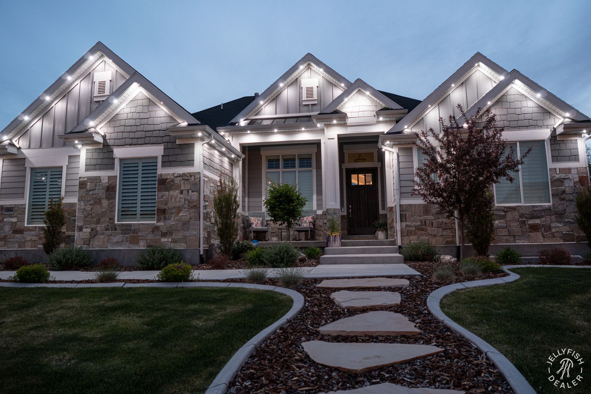 A large house with a walkway leading to it is lit up at night.