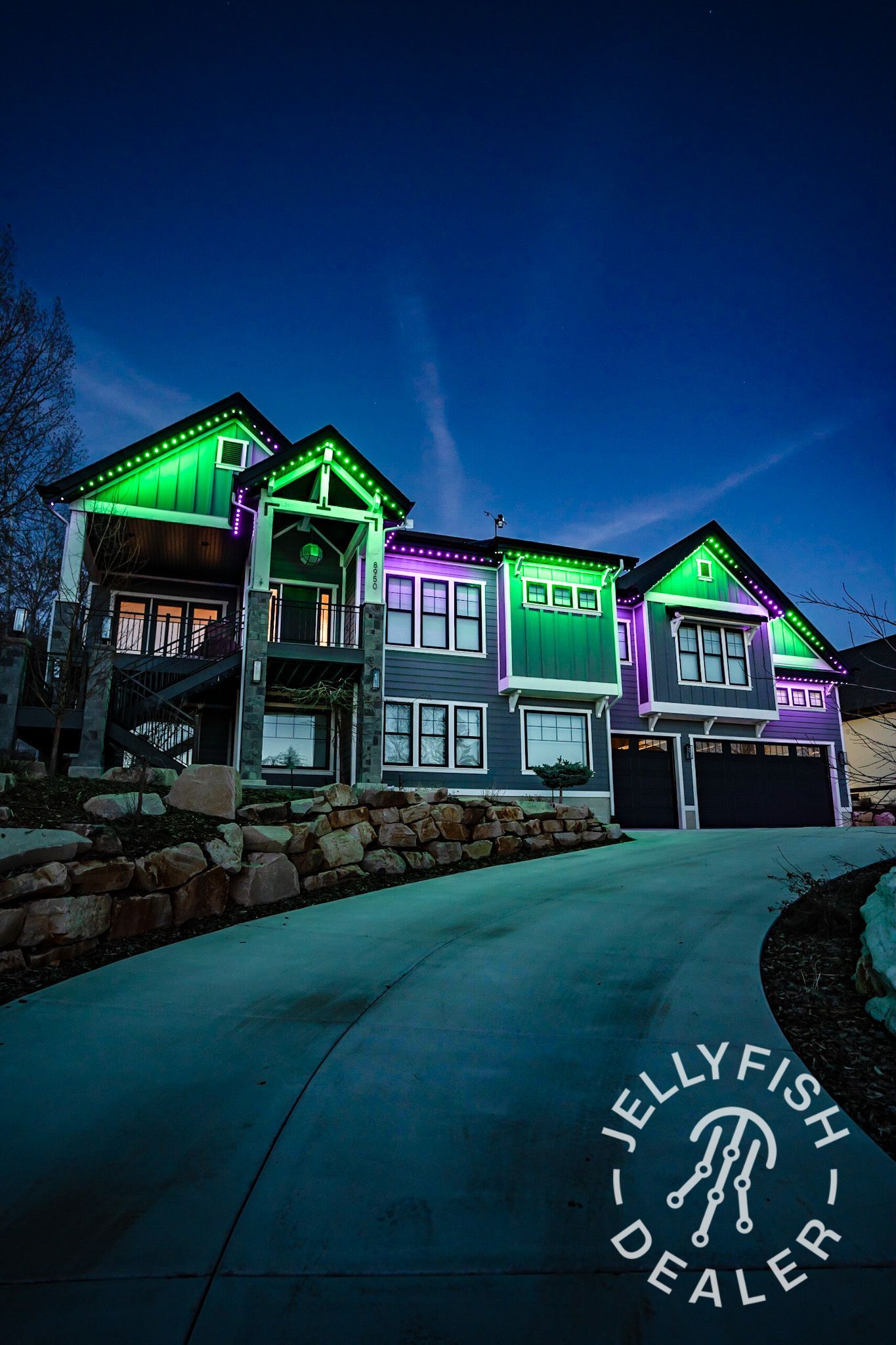 A large house is lit up with green and purple lights at night.