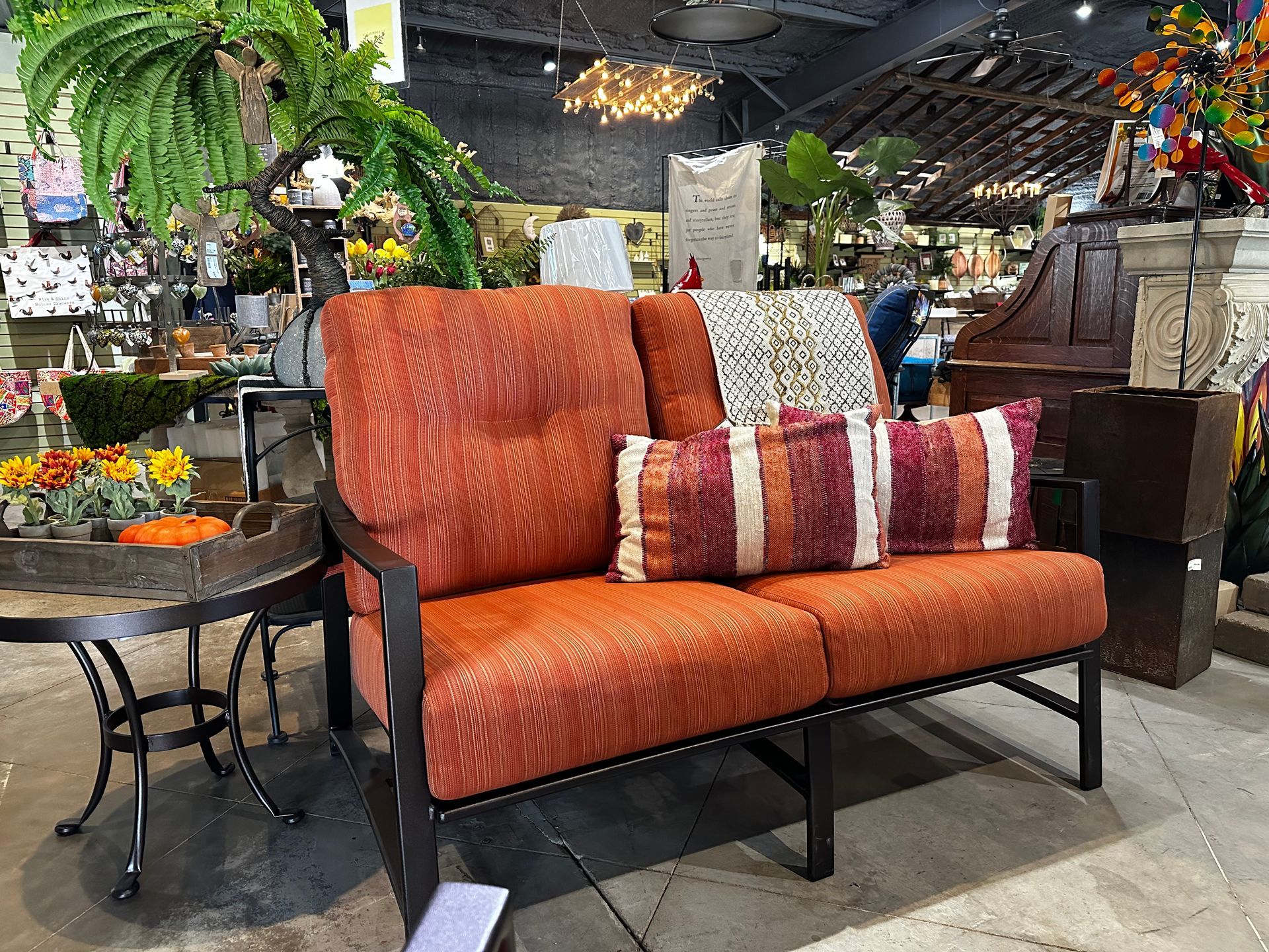 A couch with orange cushions and pillows is sitting in a room next to a table.
