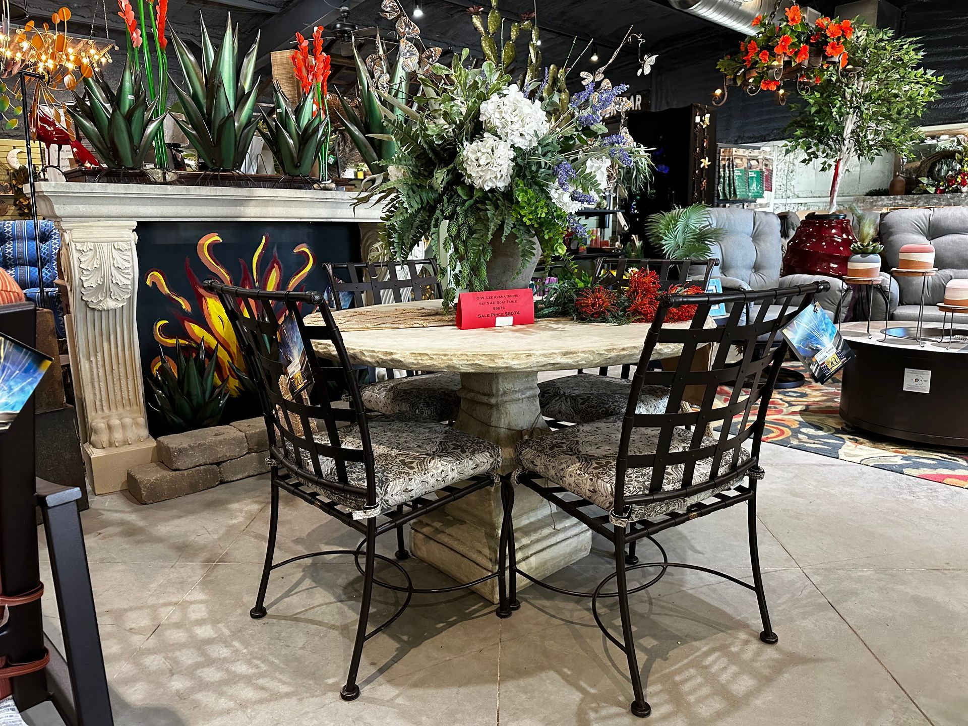 A dining room table with four chairs and a vase of flowers on it.