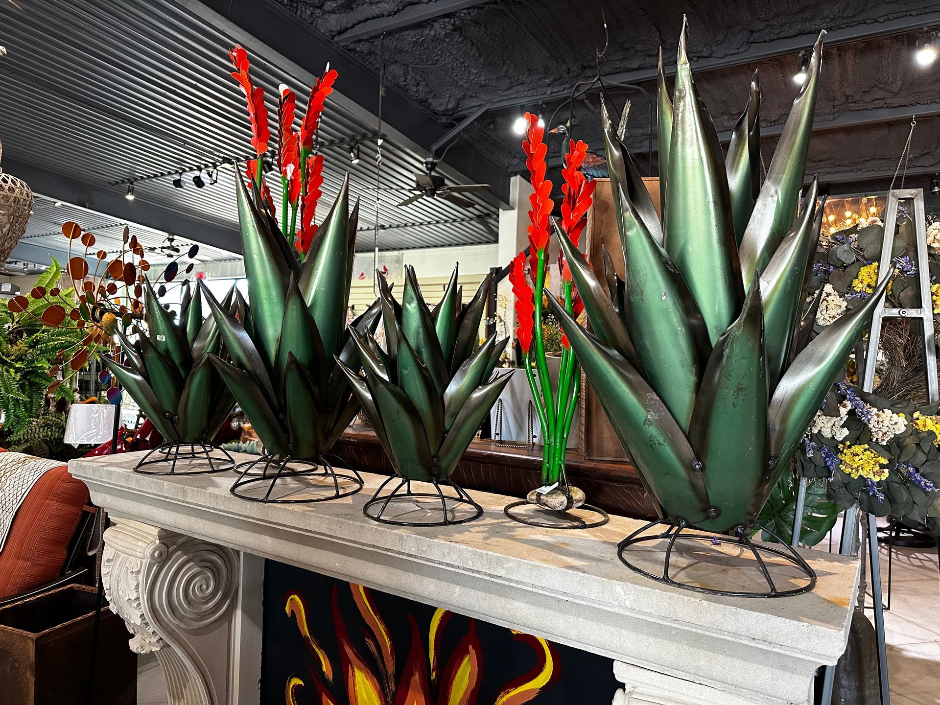 A row of green agave plants with red flowers on a table.